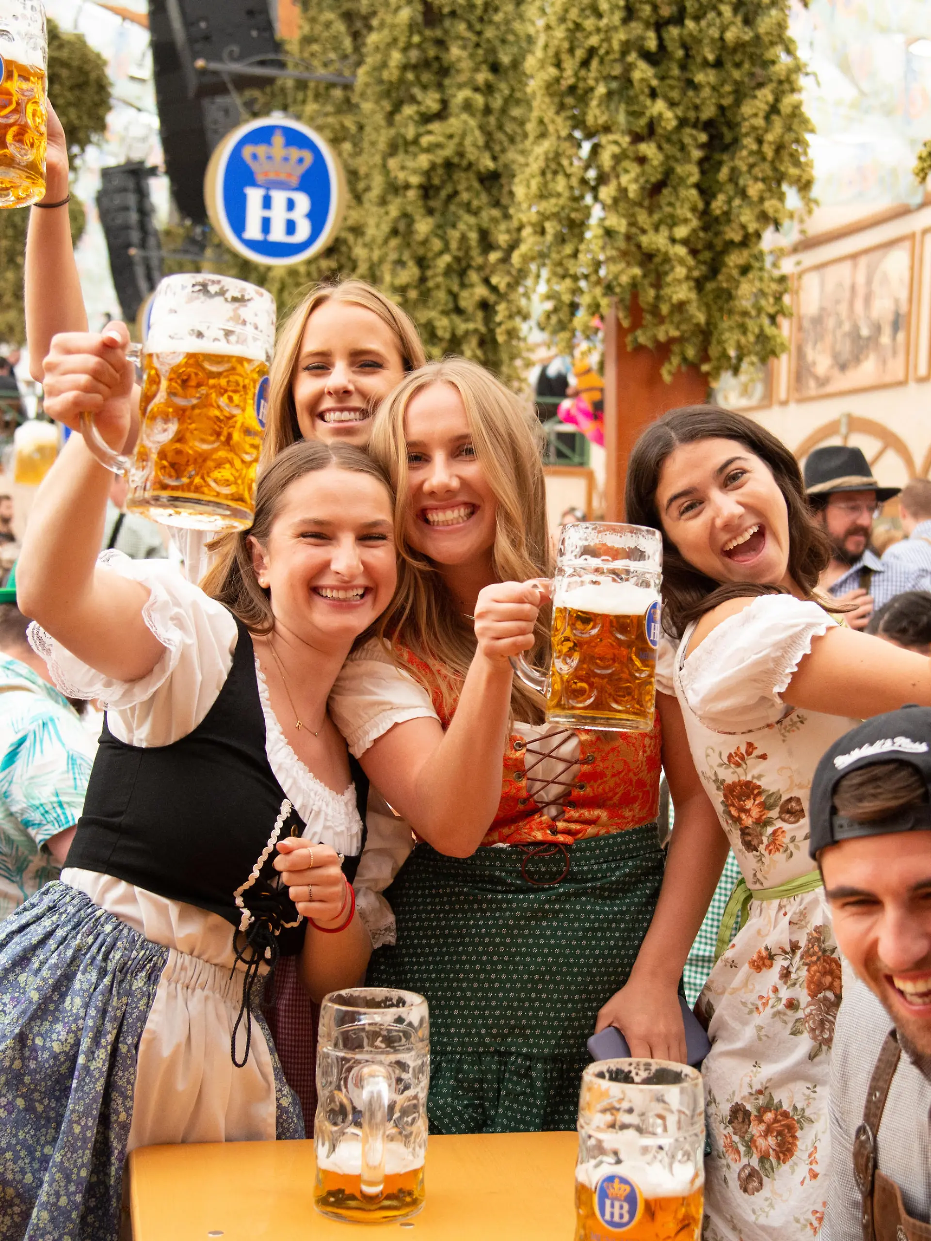 Munich, Germany - September 21, 2019: Oktoberfest in Munich, Germany. A group of young people in beer hall, celebrating Oktoberfest on Theresienwiese. People are dressed in traditional clothes and holding beer glass. The Oktoberfest is the largest fair in the world and is held annually in Munich.
