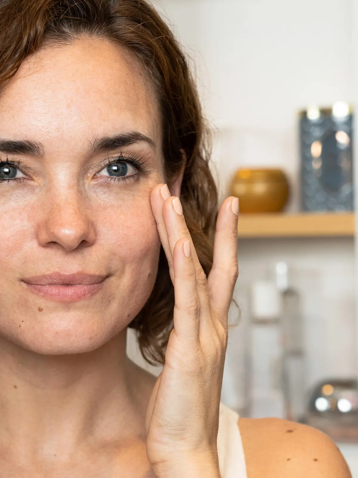 Smiling woman applying facial cream in the bathroom