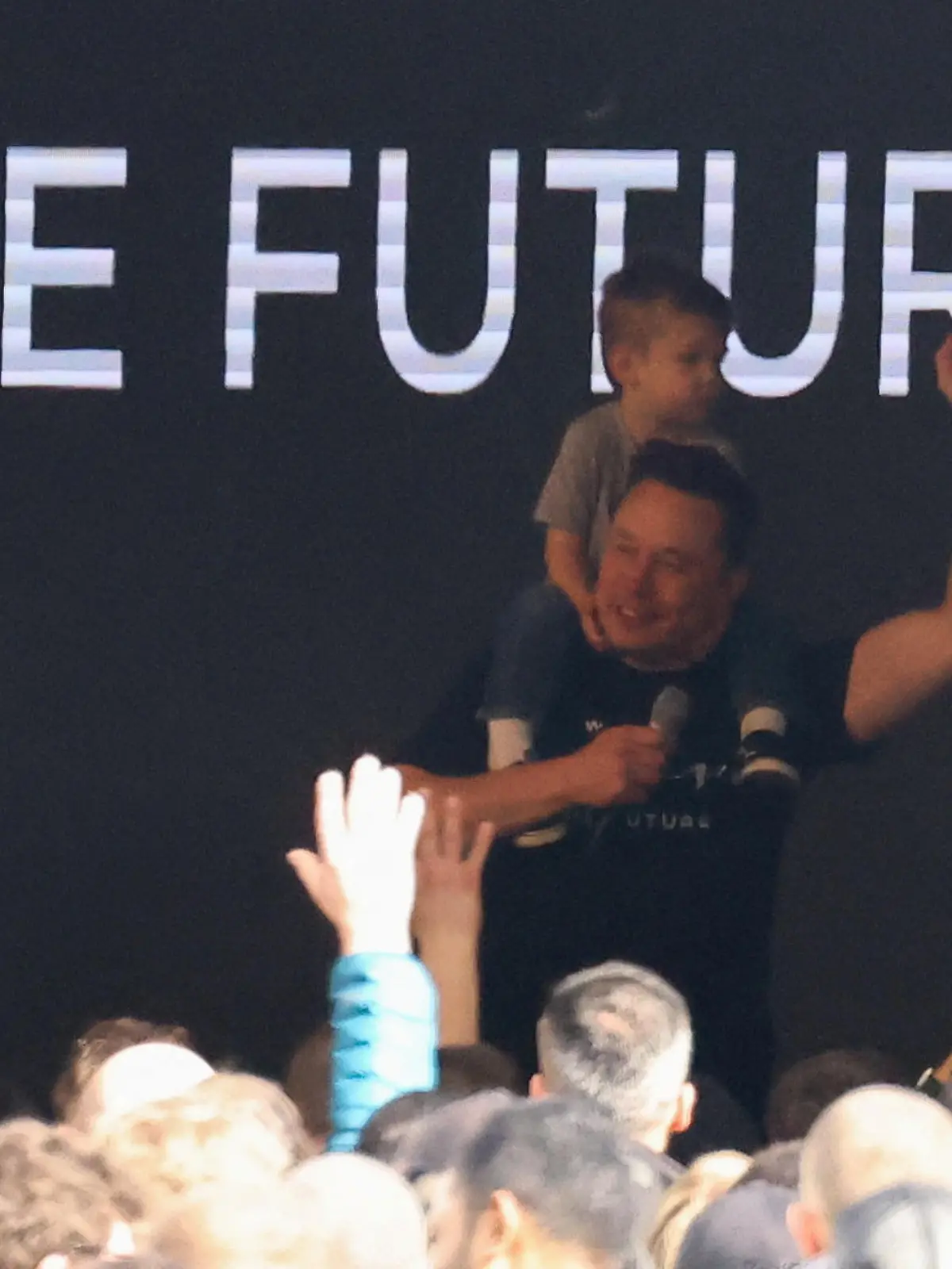 Tesla CEO Elon Musk gestures with his son X Æ A-12 on his shoulders, as he visits the carmaker's European gigafactory after an arson attack on a nearby electricity pylon that halted the Tesla production line for days, in Gruenheide near Berlin, Germany, March 13, 2024. REUTERS/Christian Mang