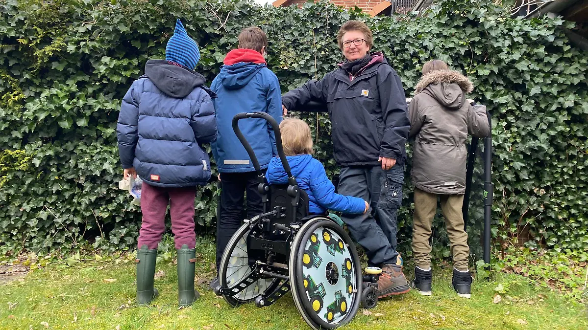 Eine Frau steht mit vier Kindern vor einem Busch