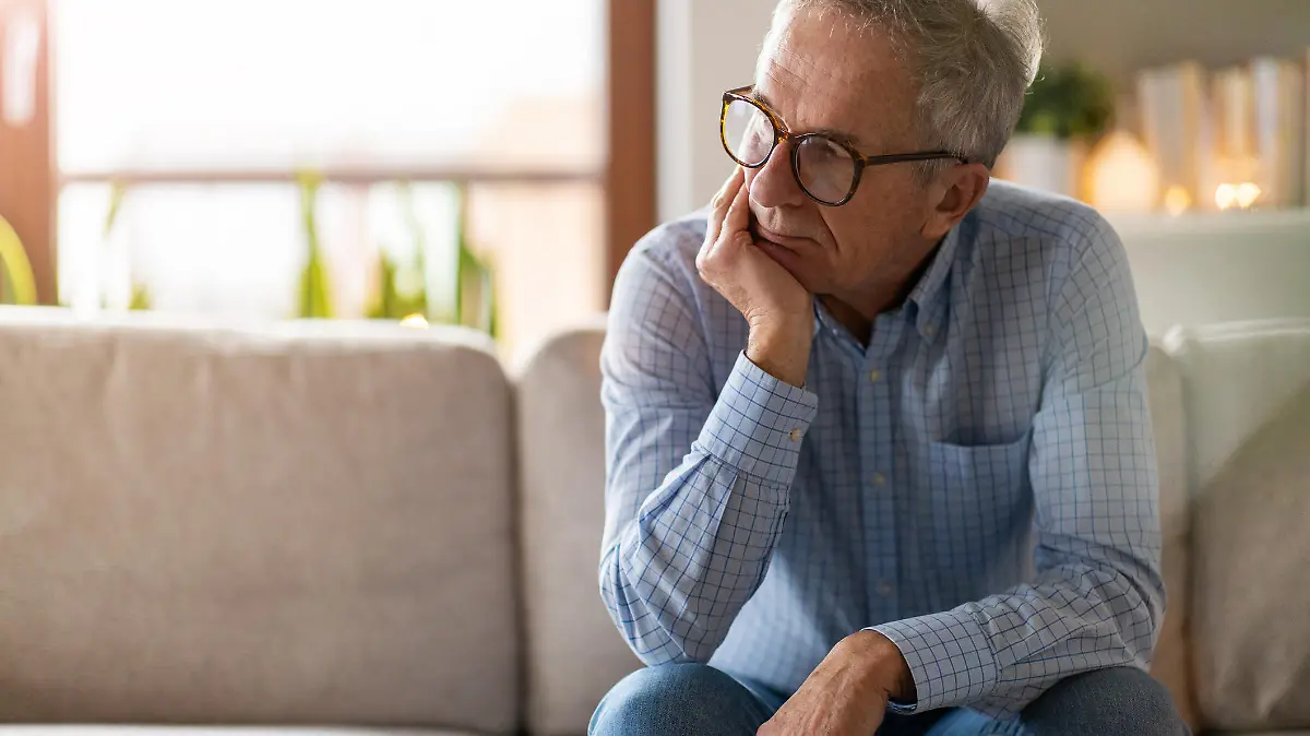 Worried senior man sitting alone in his home