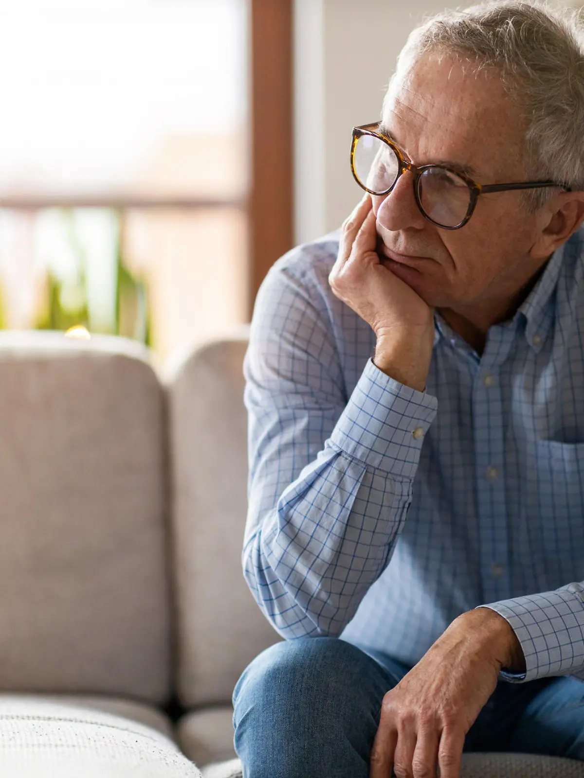 Worried senior man sitting alone in his home