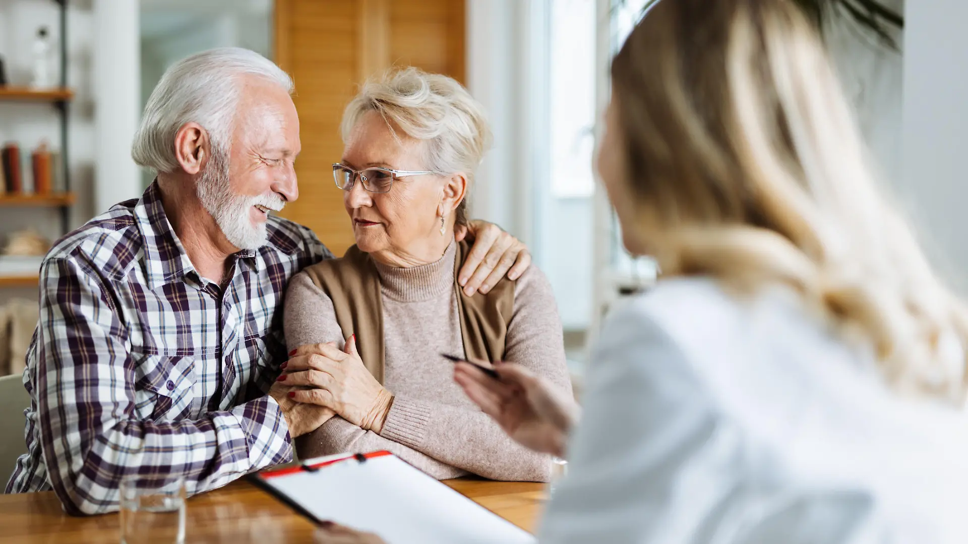 Happy mature couple talking to their doctor during her home visit