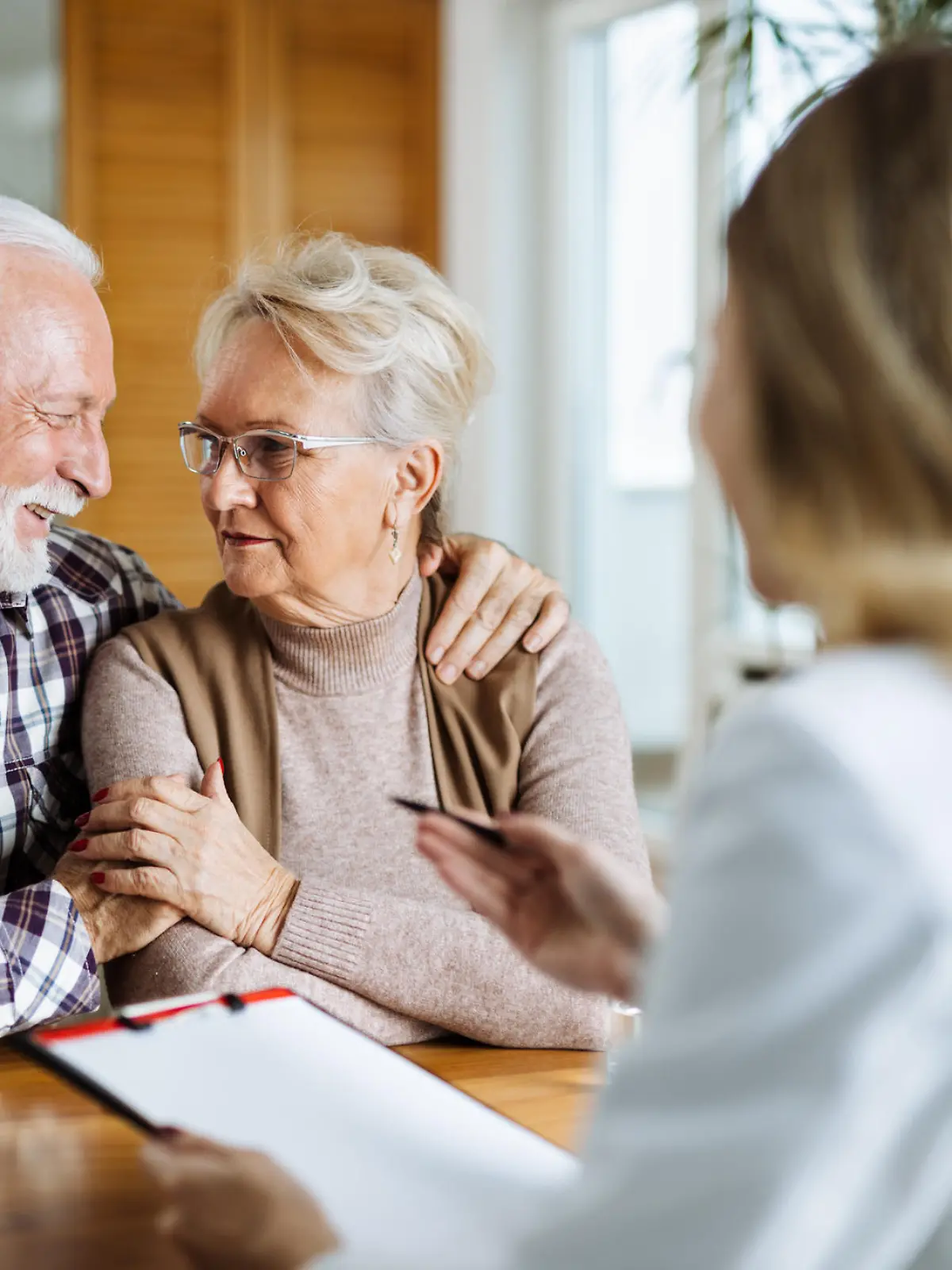 Happy mature couple talking to their doctor during her home visit