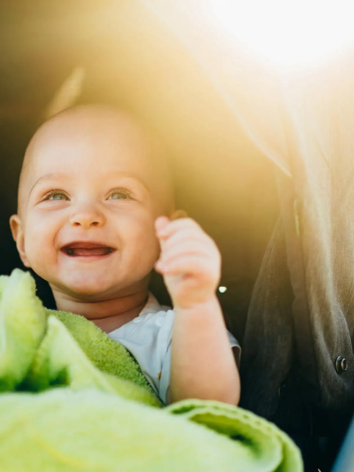 Portrait of a happy baby boy sitting in a baby stroller on the beach on a summer vacation. Baby protected from the sun. Tropical vacation.