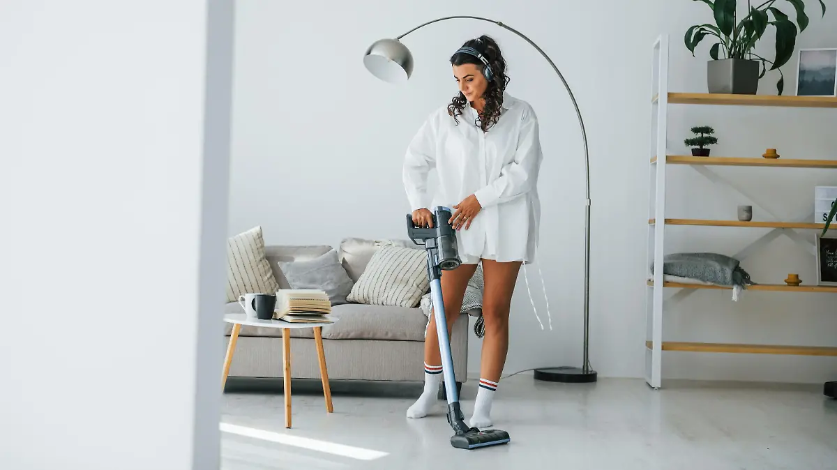 Frau mit Akkusauger im Wohnzimmer.