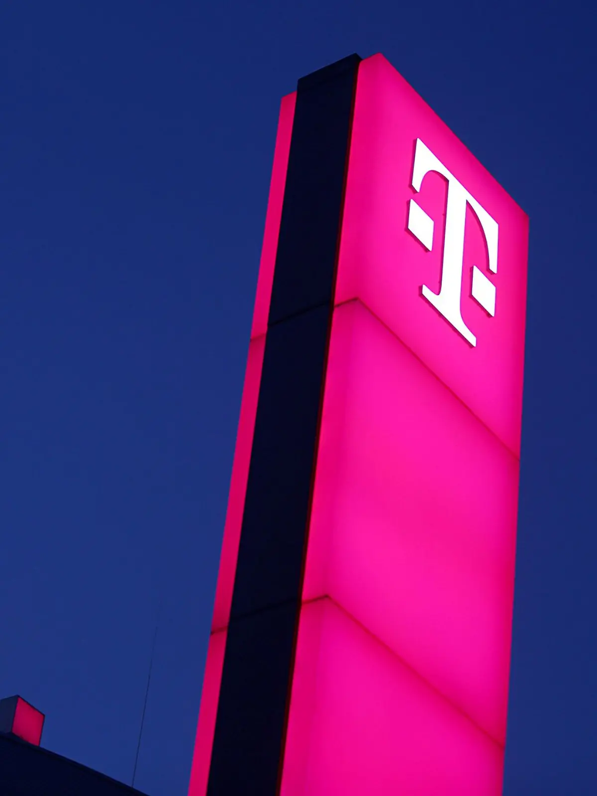Das Logo der Deutschen Telekom leuchtet auf dem Dach der Unternehmenszentrale.