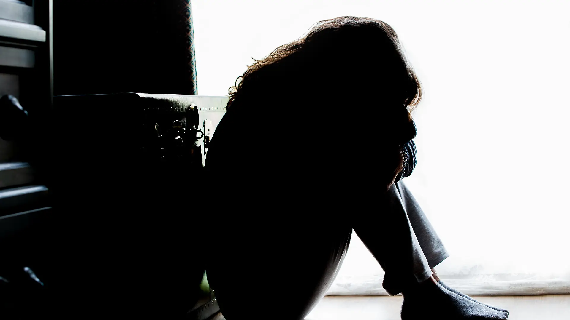 Unhappy mature lady, woman in silhouette, sitting on the floor with back lit. Depressing thoughts. || Modellfreigabe vorhanden