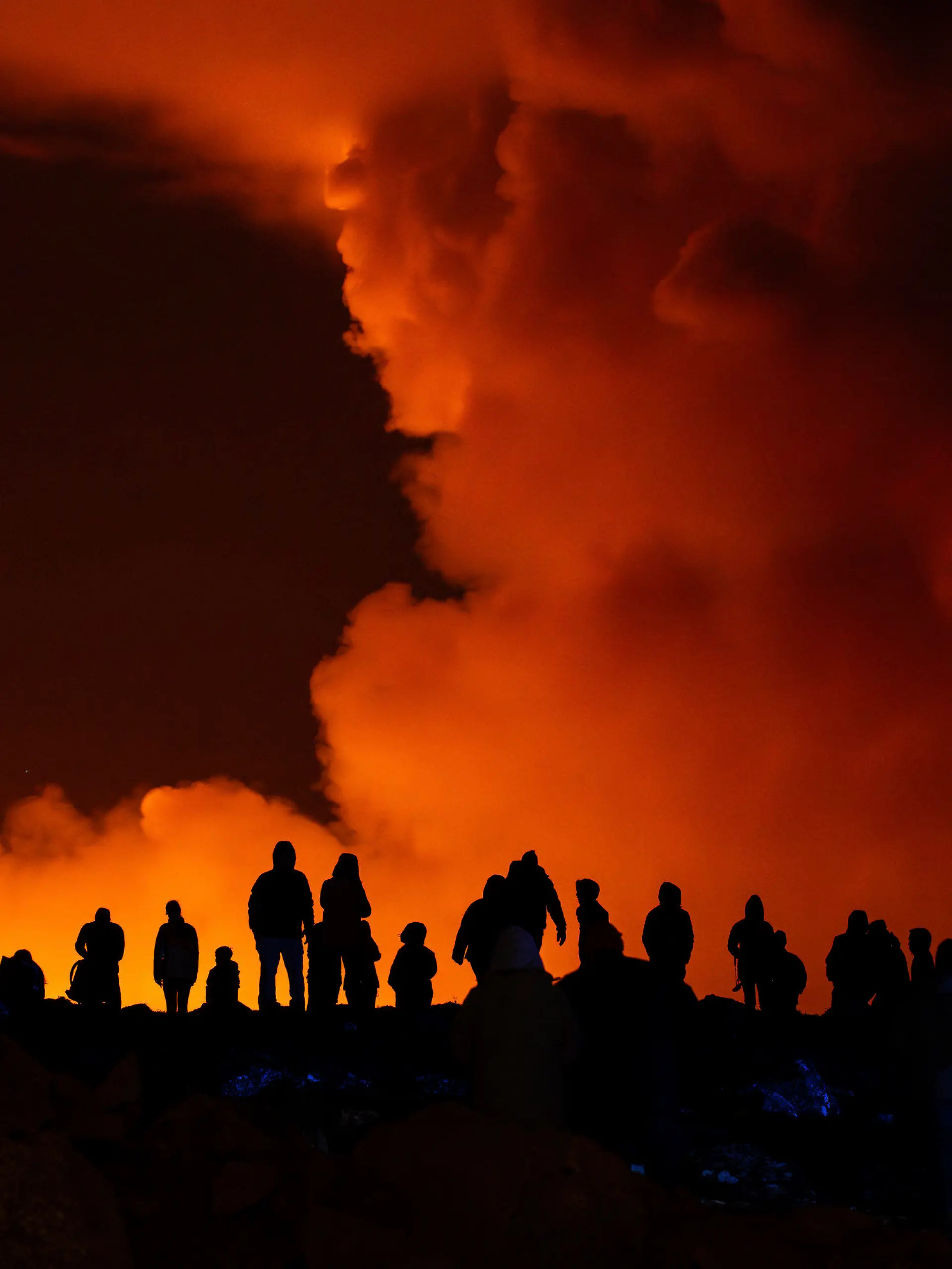 dpatopbilder - 16.03.2024, Island, Grindavík: Schaulustige beobachten die Rauchschwaden vulkanischer Aktivität zwischen Hagafell und Stóri-Skógfell. Zum vierten Mal in vier Monaten ist auf Island ein Vulkan in derselben Region ausgebrochen. Die leuchtend rote Eruption nahe dem Küstenort Grindavík war von der nordöstlich gelegenen Hauptstadt Reykjavik aus zu sehen, wie Fotos auf der Website des Senders RUV am Samstagabend zeigten. (zu dpa «Erneuter Vulkanausbruch auf Island») Foto: Marco di Marco/AP +++ dpa-Bildfunk +++