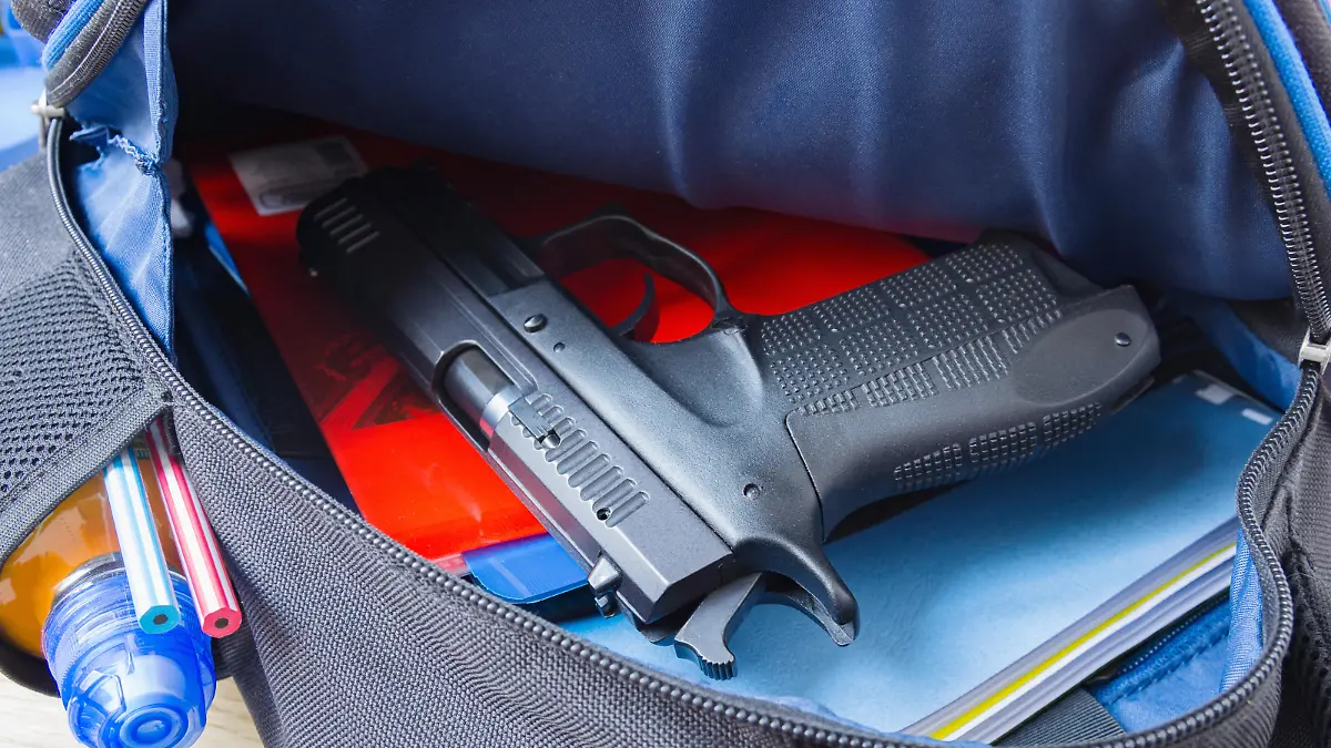 Loaded 9mm pistol in the school backpack. School shootings, gun control concept image.