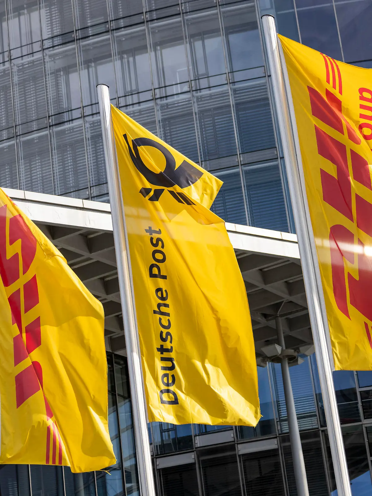 ARCHIV - 06.03.2024, Nordrhein-Westfalen, Bonn: Flaggen der Deutschen Post und der DHL Group wehen vor der Zentrale der Deutschen Post. (zu dpa: «DHL sieht internationalen Handel wieder auf dem Vormarsch») Foto: Thomas Banneyer/dpa +++ dpa-Bildfunk +++