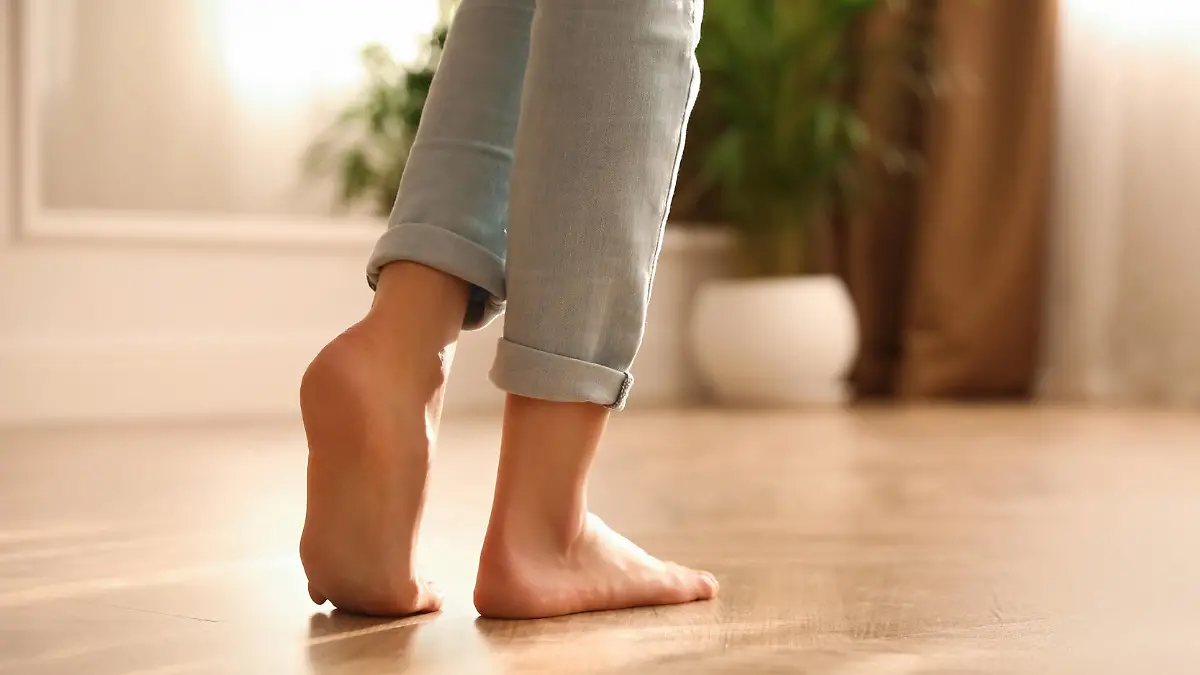 Barefoot woman at home, closeup. Floor heating system