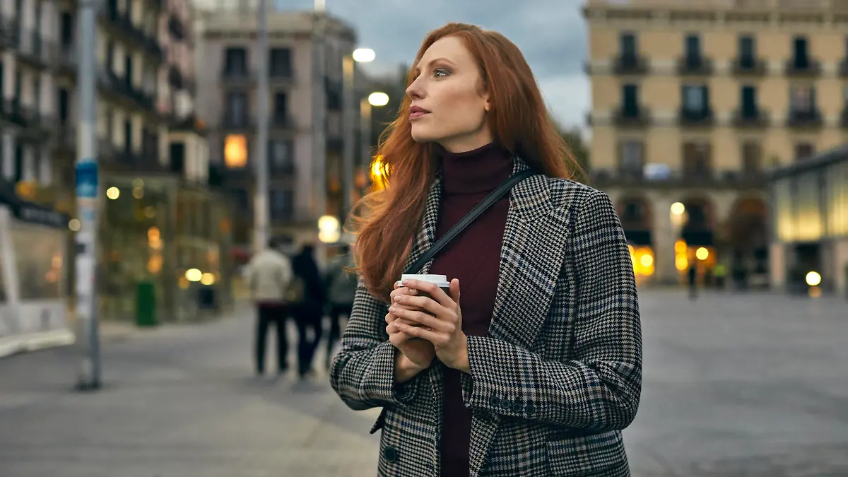 Thoughtful young women holding coffee cup. Beautiful female is in warm clothing. She is looking away.