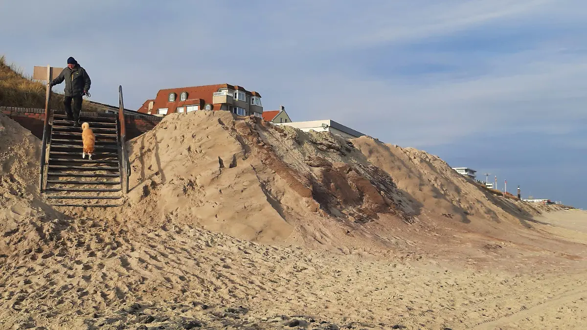 PRODUKTION - 14.03.2024, Niedersachsen, Wangerooge: Ein Mann geht mit einem Hund eine Treppe am Strand der ostfriesischen Insel Wangerooge hinab. Die bisherige Sturmflutsaison hat auf einigen Nordseeinsel deutliche Schäden an den Badestränden angerichtet. (zu dpa «Eine ziemlich Katastrophe» - Inseln fehlen nach Sturmfluten Badestrände") Foto: -/dpa +++ dpa-Bildfunk +++