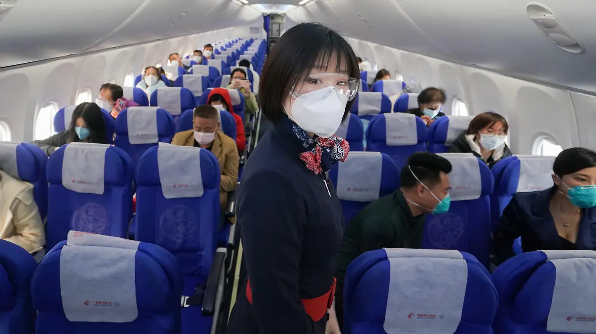 08.04.2020, China, Wuhan: Eine Flugbegleiterin mit Mundschutz steht an Bord des Fluges MU2627 vom Internationalen Flughafen Wuhan-Tianhe zwischen den Passagieren. Die Reisebeschränkungen in der Stadt wurden nach fast 11 Wochen wieder aufgehoben. Foto: Cheng Min/XinHua/dpa +++ dpa-Bildfunk +++