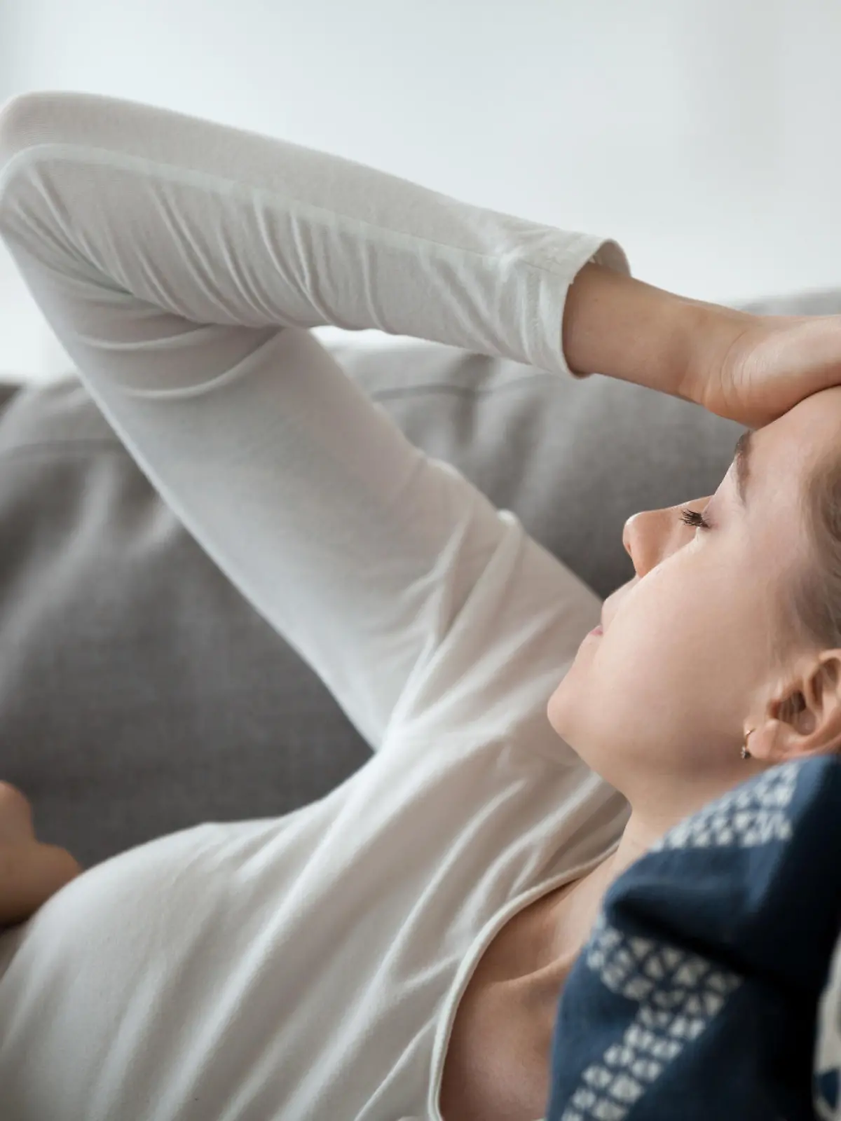 Upset depressed young woman lying on couch feeling strong headache migraine, sad tired drowsy teenager exhausted girl resting trying to sleep after nervous tension and stress, somnolence concept