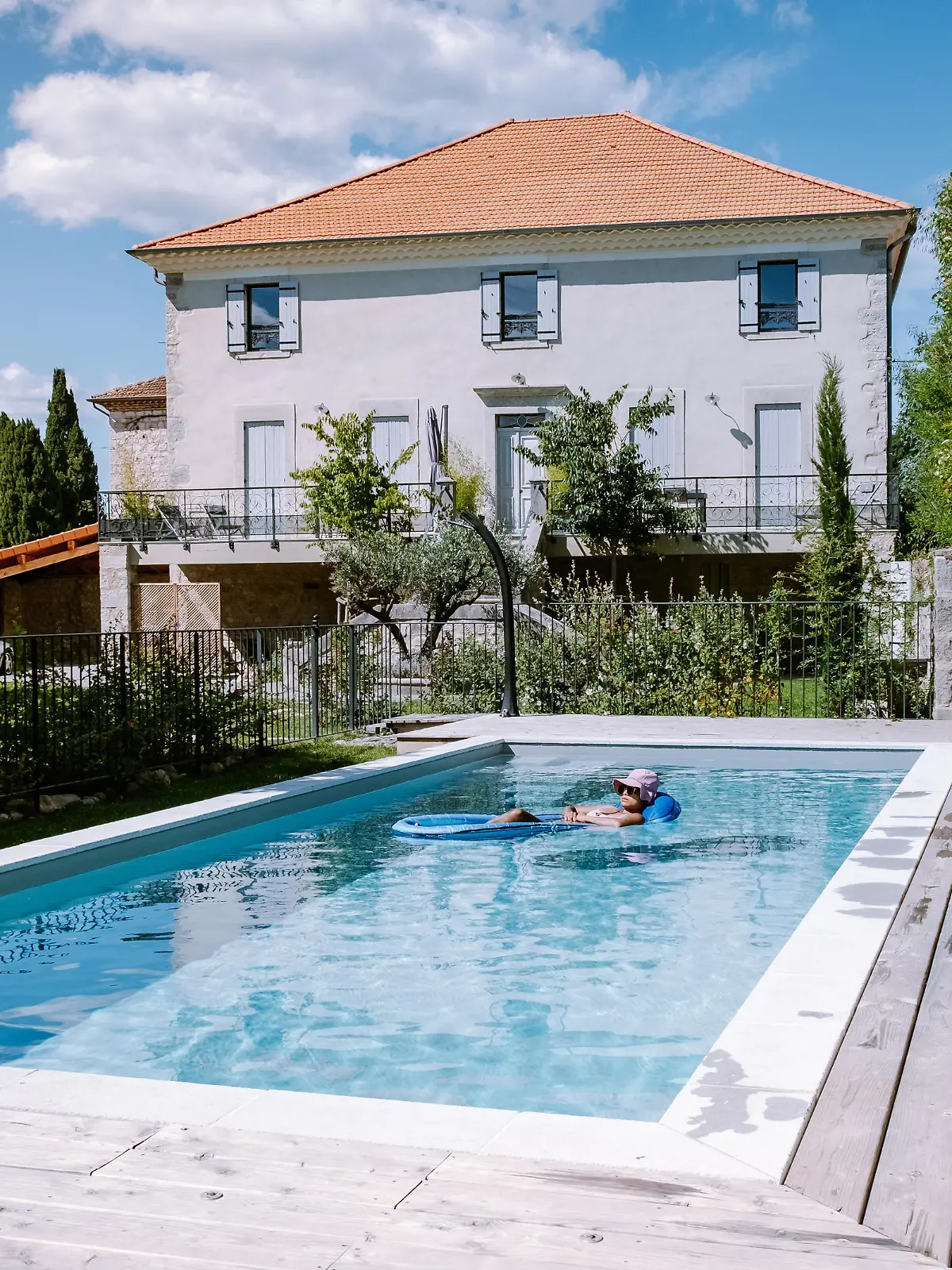 French vacation home with wooden deck and swimming pool in the Ardeche France Europe. woman relaxing by the pool with wooden deck during luxury vacation at an holiday home in South of France