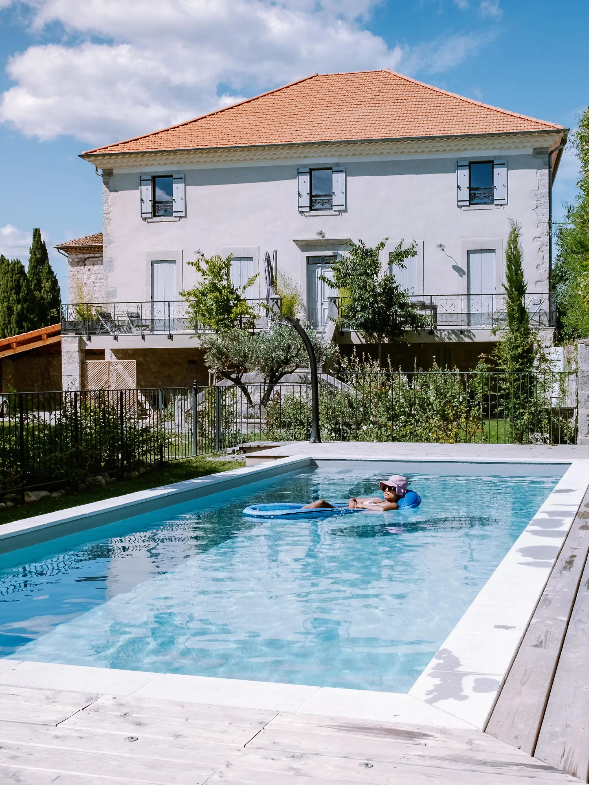 French vacation home with wooden deck and swimming pool in the Ardeche France Europe. woman relaxing by the pool with wooden deck during luxury vacation at an holiday home in South of France