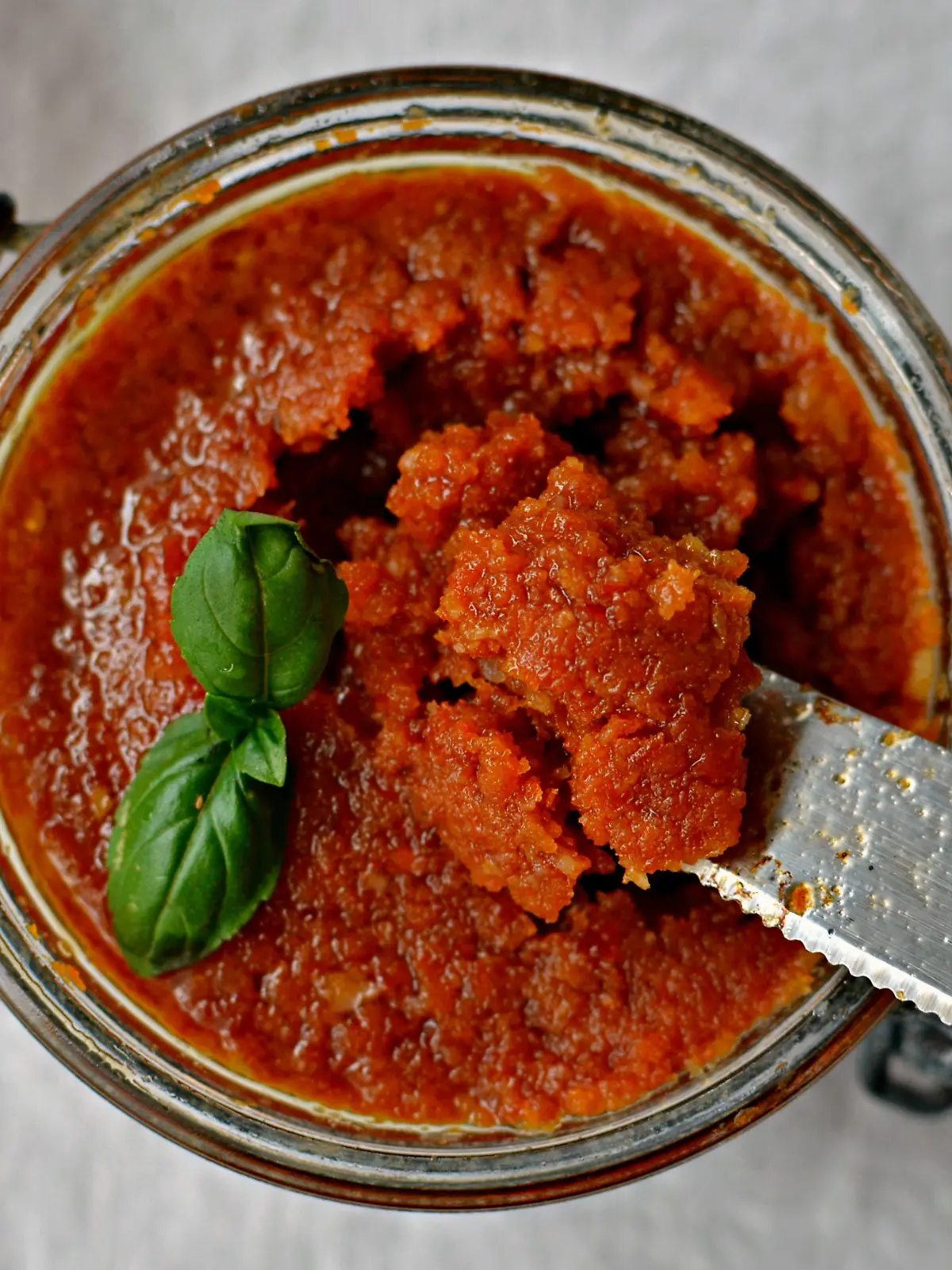 Sun-dried tomato and almond pesto - Pesto rosso sauce in a jar with knife, top view