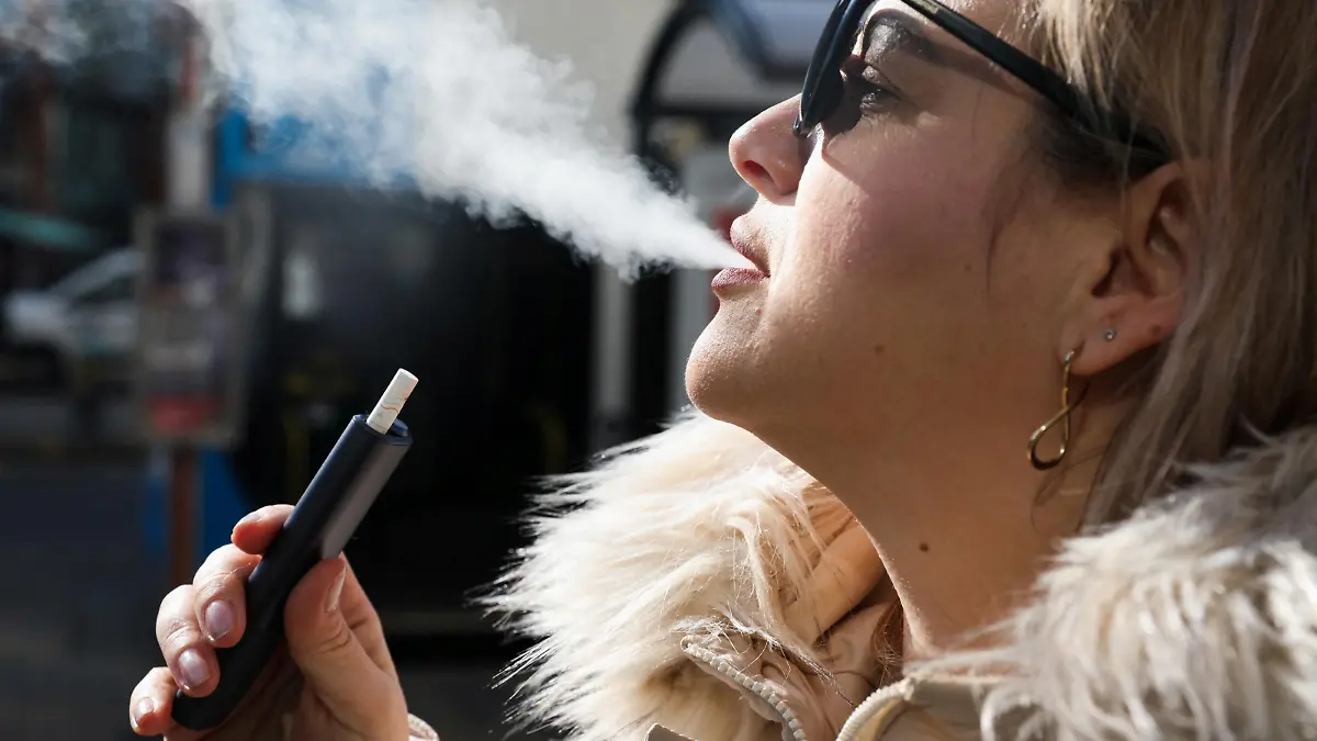 A woman holds an e-cigarette as she vapes on a street in Manchester, Britain March 6, 2024. REUTERS/Temilade Adelaja