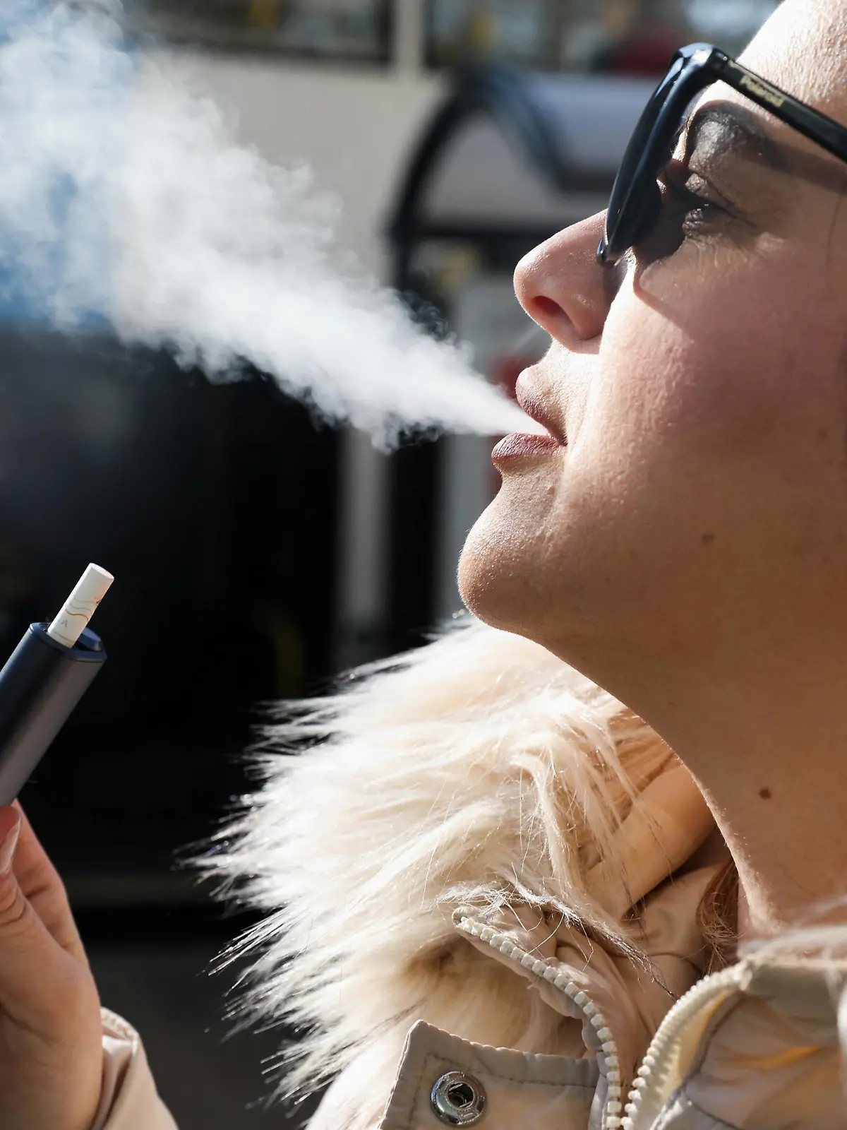 A woman holds an e-cigarette as she vapes on a street in Manchester, Britain March 6, 2024. REUTERS/Temilade Adelaja