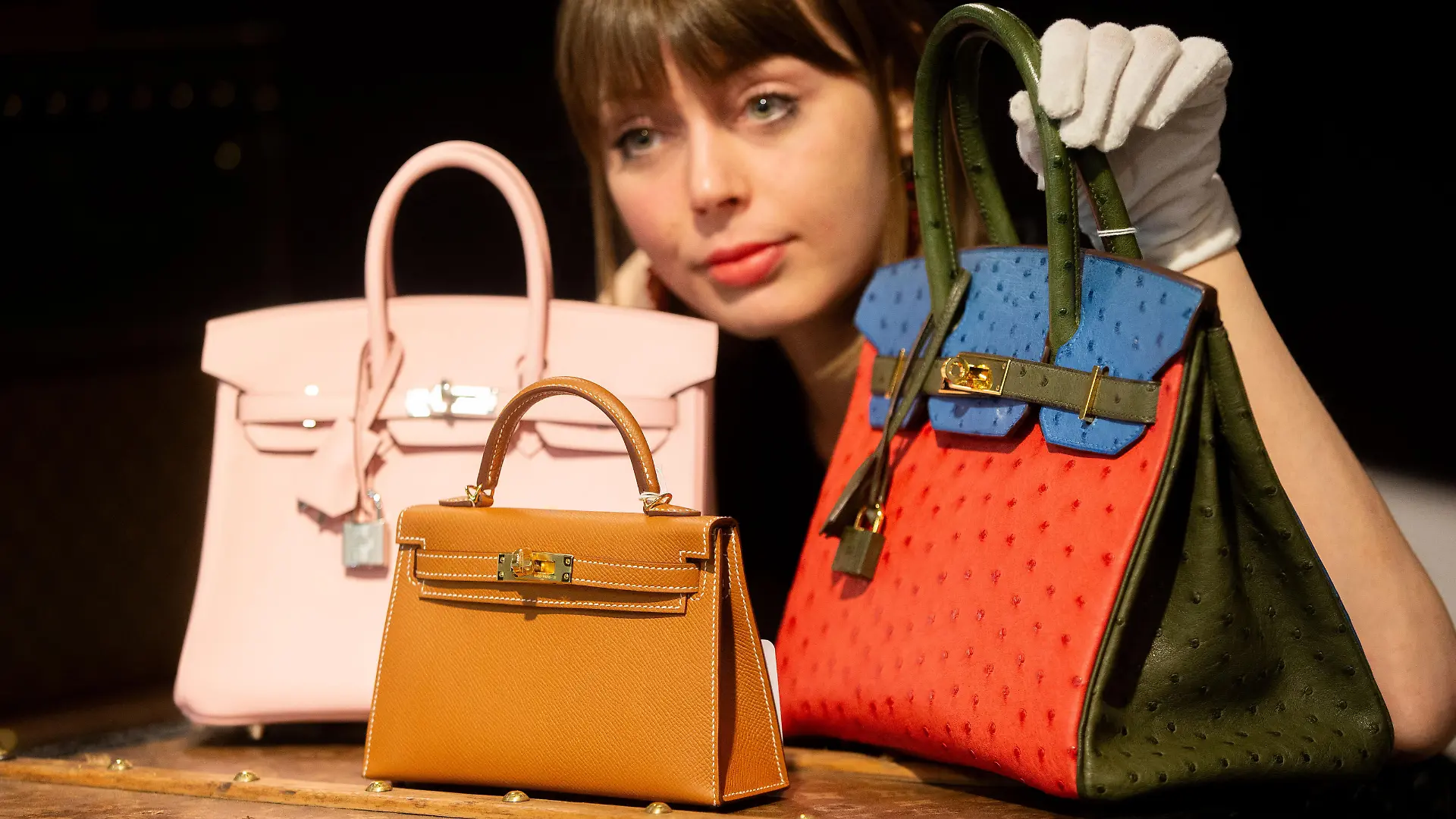 February 26, 2024, London, England, United Kingdom: A staff member with (L to R) a HermÃÂ_s: Rose Sakura Swift Leather Birkin 25, 2023, (Est. ÃÂ£18,000 - ÃÂ£22,000), a HermÃÂ_s: Gold Epsom Leather Mini Kelly II 20, 2023, (Est. ÃÂ£18,000 - ÃÂ£22,000) and a HermÃÂ_s: Special Order Tri-Colour Ostrich Birkin 30 Horseshoe Stamp (HSS), 2012, (Est. ÃÂ£18,000 - ÃÂ£22,000) at a preview of Bonhams upcoming Designer Handbags and Fashion sale. (Credit Image: Â© Tayfun Salci/ZUMA Press Wire