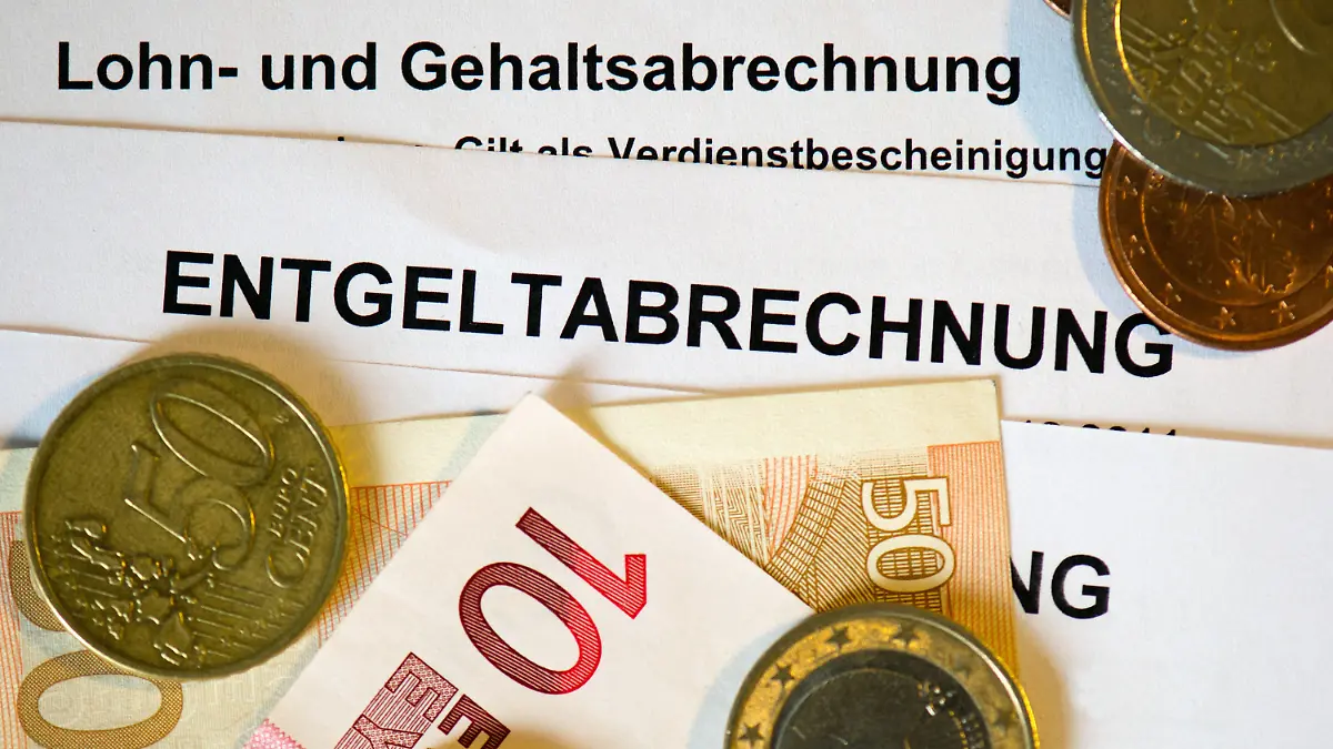 ARCHIV - 30.01.2013, Sachsen, Dresden: Auf Lohn- und Gehaltsabrechnungen (Entgeltabrechnungen) liegen Euromünzen und Eurogeldscheine. (zu dpa: «Sachsen haben trotz Inflation etwas mehr Geld in der Tasche») Foto: Arno Burgi/dpa-Zentralbild/dpa +++ dpa-Bildfunk +++