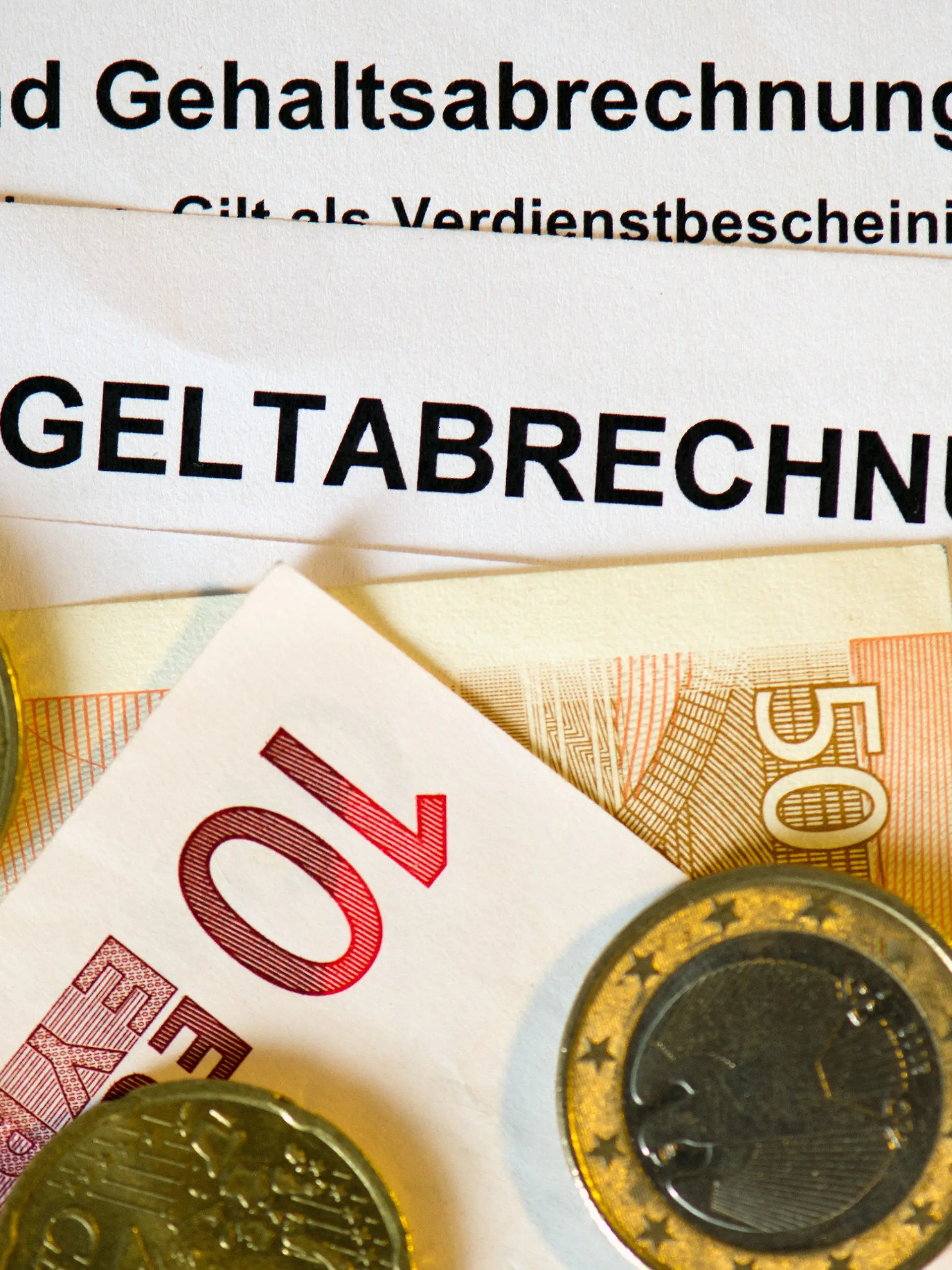 ARCHIV - 30.01.2013, Sachsen, Dresden: Auf Lohn- und Gehaltsabrechnungen (Entgeltabrechnungen) liegen Euromünzen und Eurogeldscheine. (zu dpa: «Sachsen haben trotz Inflation etwas mehr Geld in der Tasche») Foto: Arno Burgi/dpa-Zentralbild/dpa +++ dpa-Bildfunk +++