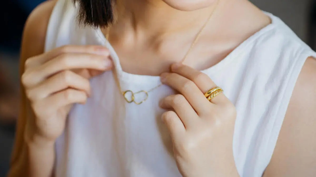 Close-up shot of portrait of a gorgeous young woman trying on a gold necklace at a jewelry and fashion shop