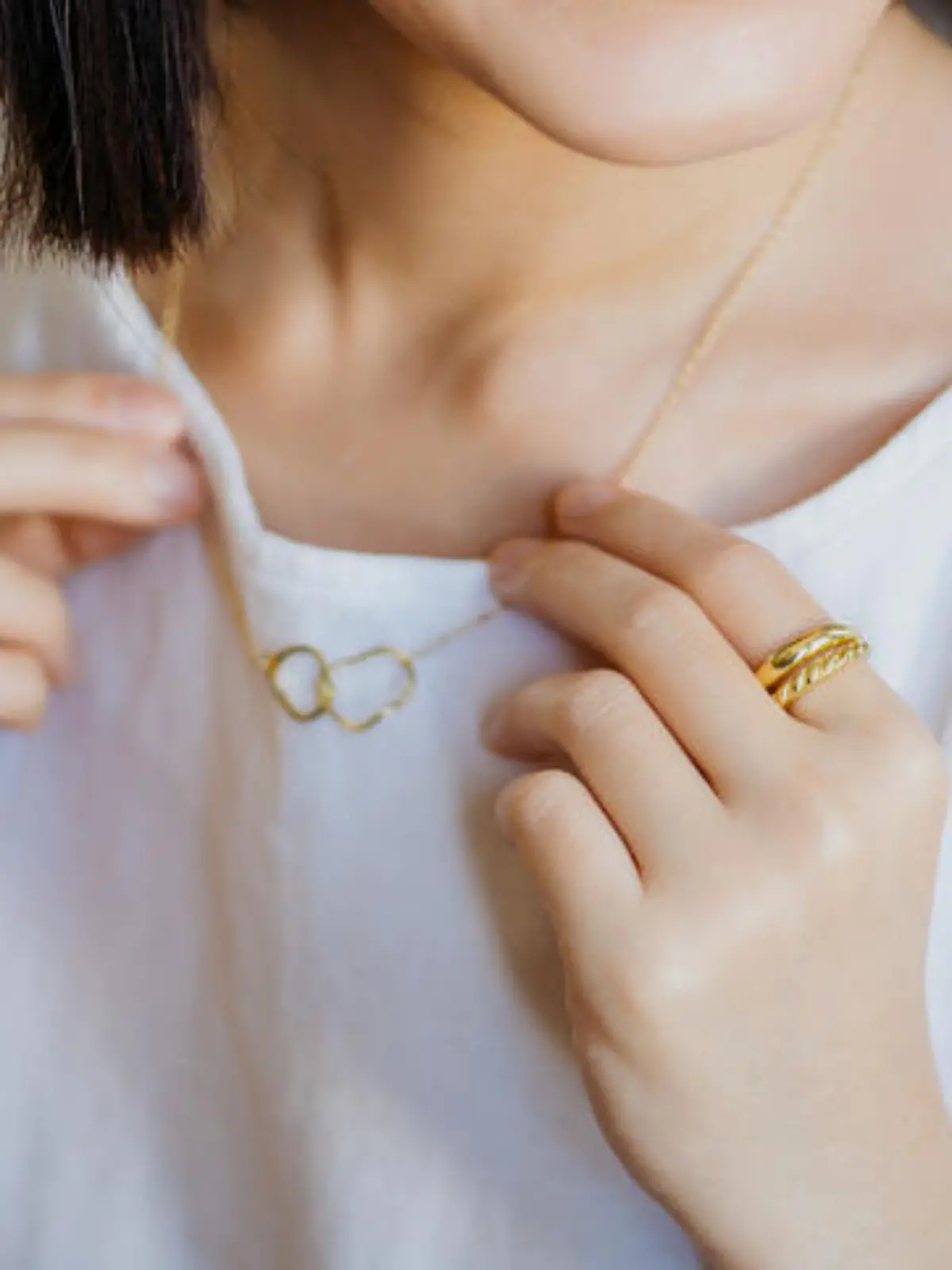 Close-up shot of portrait of a gorgeous young woman trying on a gold necklace at a jewelry and fashion shop