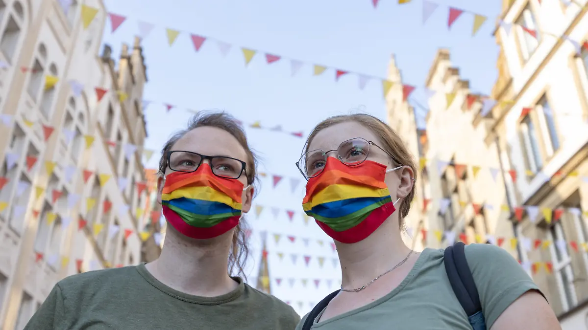 02.09.2022, Nordrhein-Westfalen, Münster: Menschen mit Mundschutz in den Farben des Regenbogens, als ein Symbol der LGBT-Bewegung, demonstrieren auf dem Prinzipalmarkt gegen Gewalt an queeren Menschen. Ein 25 Jahre alter Mann war bei einer Christopher-Street-Day-Versammlung in Münster brutal niedergeschlagen und schwer verletzt worden. Später ist er im Krankenhaus seinen Verletzungen erlegen. Der Täter ist noch nicht gestellt. Foto: Friso Gentsch/dpa +++ dpa-Bildfunk +++