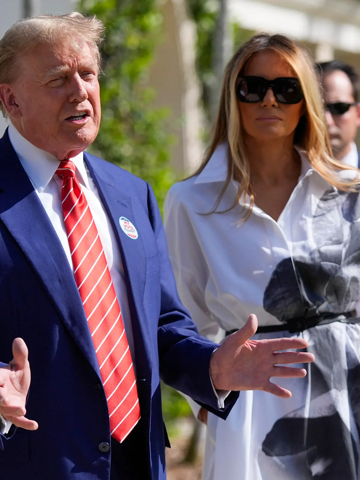 ARCHIV - 19.03.2024, USA, Palmenstrand: Der republikanische Präsidentschaftskandidat und ehemalige US-Präsident Donald Trump (l) unterhält sich mit der ehemaligen First Lady Melania Trump, als sie nach der Stimmabgabe bei den Vorwahlen das Gebäude verlassen. Melania Trump trat in den vergangenen Monaten nur sehr selten öffentlich in Erscheinung. (zu dpa: «Wo ist Melania? Trumps Ehefrau und ihre Rolle im Wahlkampf») Foto: Wilfredo Lee/AP/dpa +++ dpa-Bildfunk +++