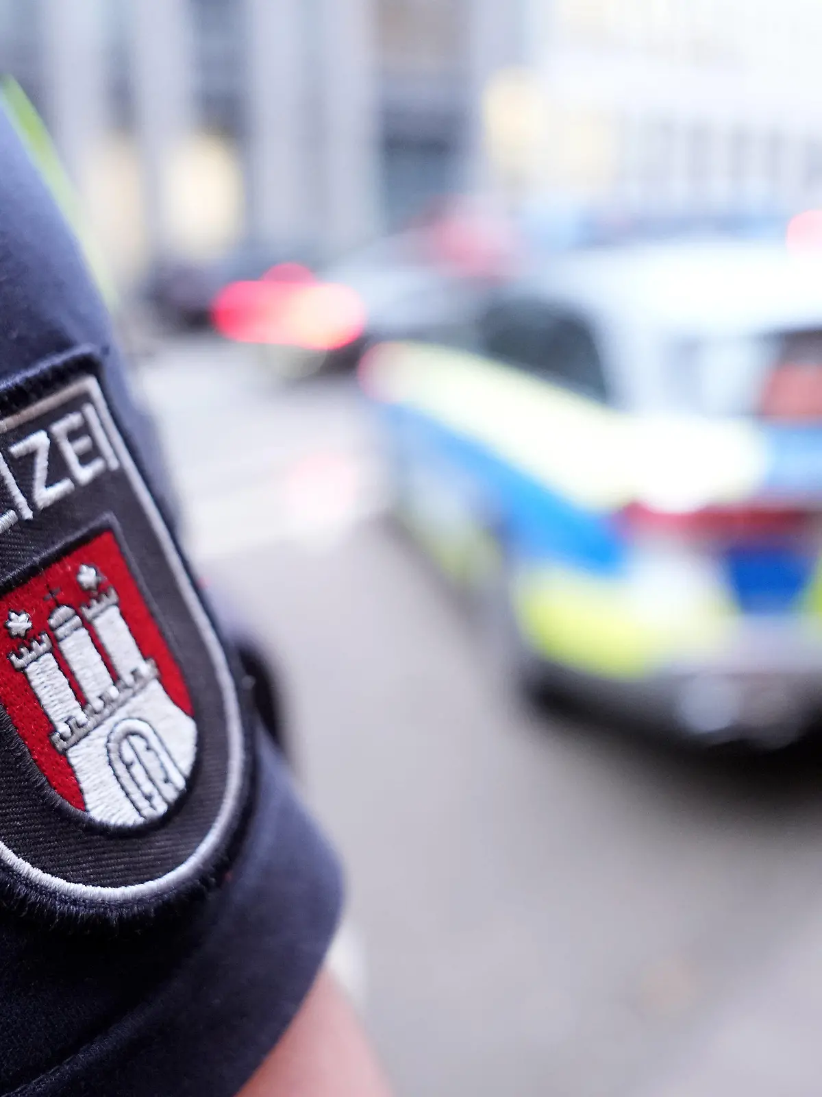 ARCHIV - 15.03.2024, Hamburg: ILLUSTRATION - Ein Polizist steht vor einem Einsatzfahrzeug der Polizei. (zu dpa: «Kleiner, dicker, älter: Hamburgs Polizei ändert Anforderungsprofil») Foto: Marcus Brandt/dpa +++ dpa-Bildfunk +++