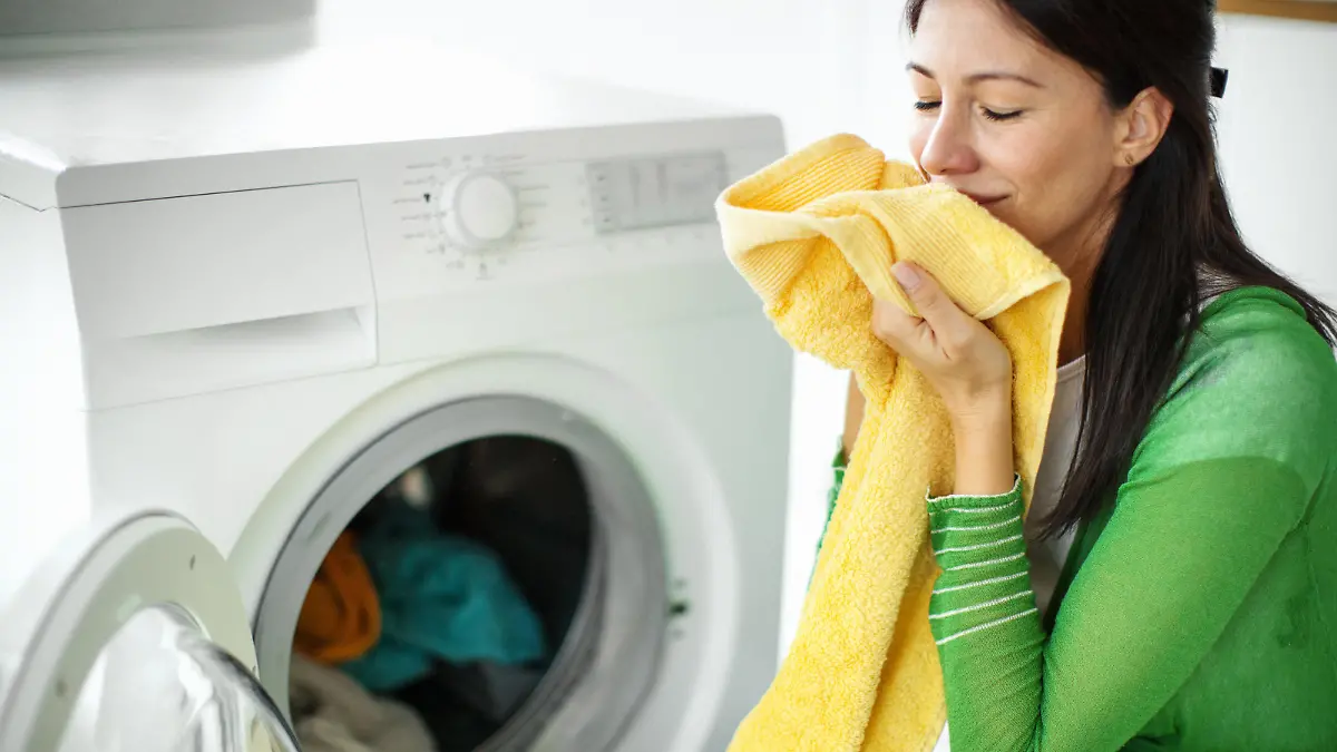 Closeup of an early 30's brunette woman doing laundry at home and enjoying nice smell of clean laundry.