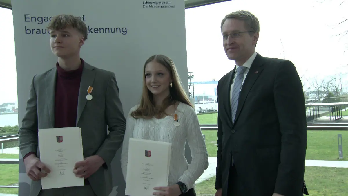 Hanna und Paul erhalten von Ministerpräsident Daniel Günther die Rettungsmedaille am Bande.