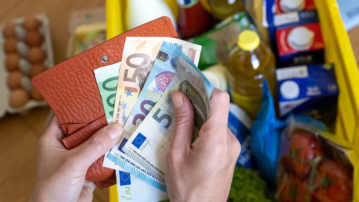 ARCHIV - 02.06.2022, Sachsen, Leipzig: Eine Einkaufskiste mit Lebensmitteln steht auf einem Küchentisch, während eine Frau Euro-Banknoten in den Händen hält. Das Leben in Deutschland hat sich in den vergangenen Monaten deutlich verteuert. Der Staat versucht, die Menschen zu entlasten. Doch schon im Herbst könnte die Inflation neue Höhen erreichen. (zu dpa «Inflation weiter auf hohem Niveau - Anstieg im Herbst erwartet») Foto: Hendrik Schmidt/dpa +++ dpa-Bildfunk +++
