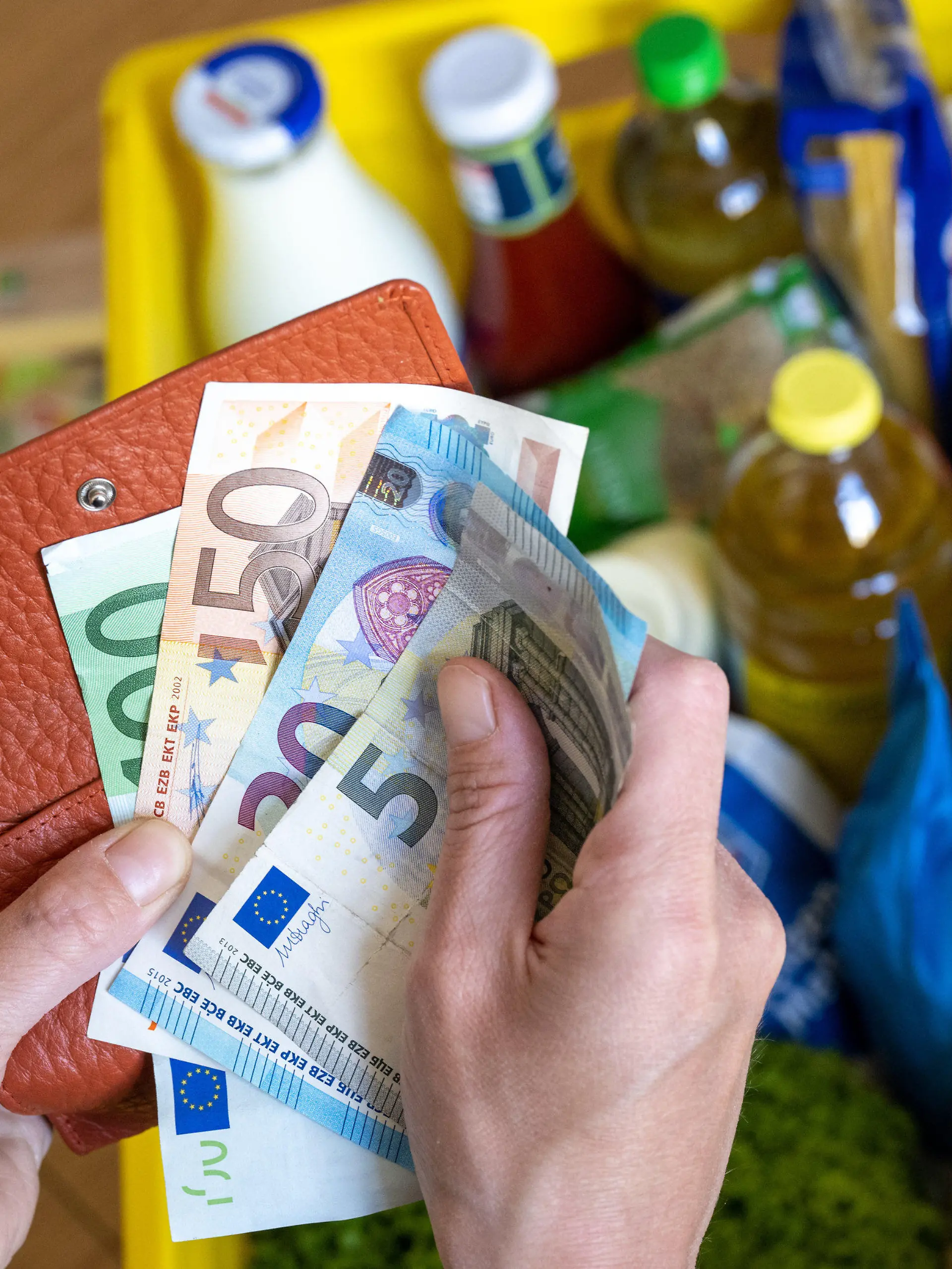 ARCHIV - 02.06.2022, Sachsen, Leipzig: Eine Einkaufskiste mit Lebensmitteln steht auf einem Küchentisch, während eine Frau Euro-Banknoten in den Händen hält. Das Leben in Deutschland hat sich in den vergangenen Monaten deutlich verteuert. Der Staat versucht, die Menschen zu entlasten. Doch schon im Herbst könnte die Inflation neue Höhen erreichen. (zu dpa «Inflation weiter auf hohem Niveau - Anstieg im Herbst erwartet») Foto: Hendrik Schmidt/dpa +++ dpa-Bildfunk +++