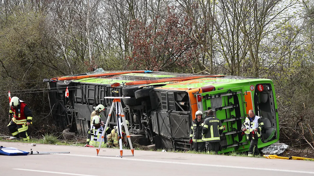 27.03.2024, Sachsen, Schkeuditz: Ein Reisebus liegt zur Seite gekippt an der Unfallstelle auf der A9. Bei einem Unfall mit einem Reisebus auf der A9 nahe Leipzig sind mindestens fünf Menschen ums Leben gekommen. Dies teilte die Polizei auf Anfrage mit. Zudem gab es bei dem Unfall am Mittwoch zahlreiche Verletzte. Foto: Jan Woitas/dpa +++ dpa-Bildfunk +++