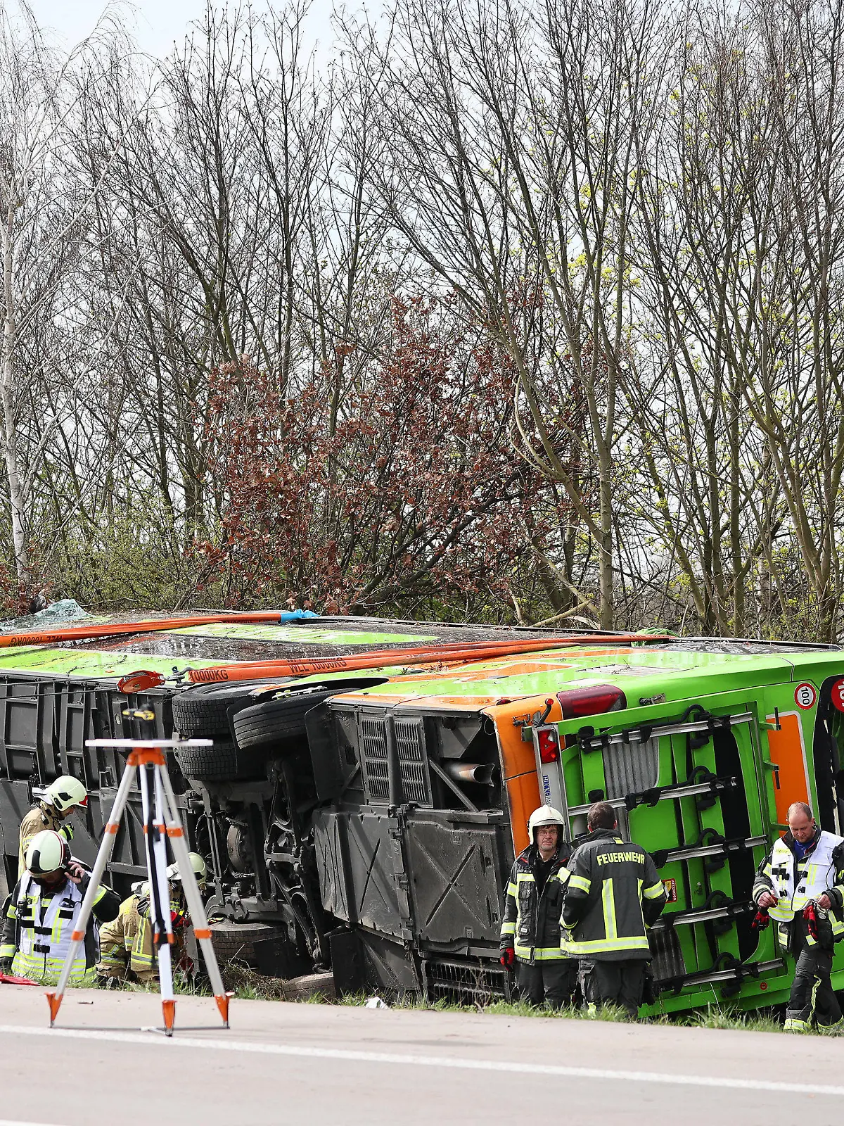 27.03.2024, Sachsen, Schkeuditz: Ein Reisebus liegt zur Seite gekippt an der Unfallstelle auf der A9. Bei einem Unfall mit einem Reisebus auf der A9 nahe Leipzig sind mindestens fünf Menschen ums Leben gekommen. Dies teilte die Polizei auf Anfrage mit. Zudem gab es bei dem Unfall am Mittwoch zahlreiche Verletzte. Foto: Jan Woitas/dpa +++ dpa-Bildfunk +++