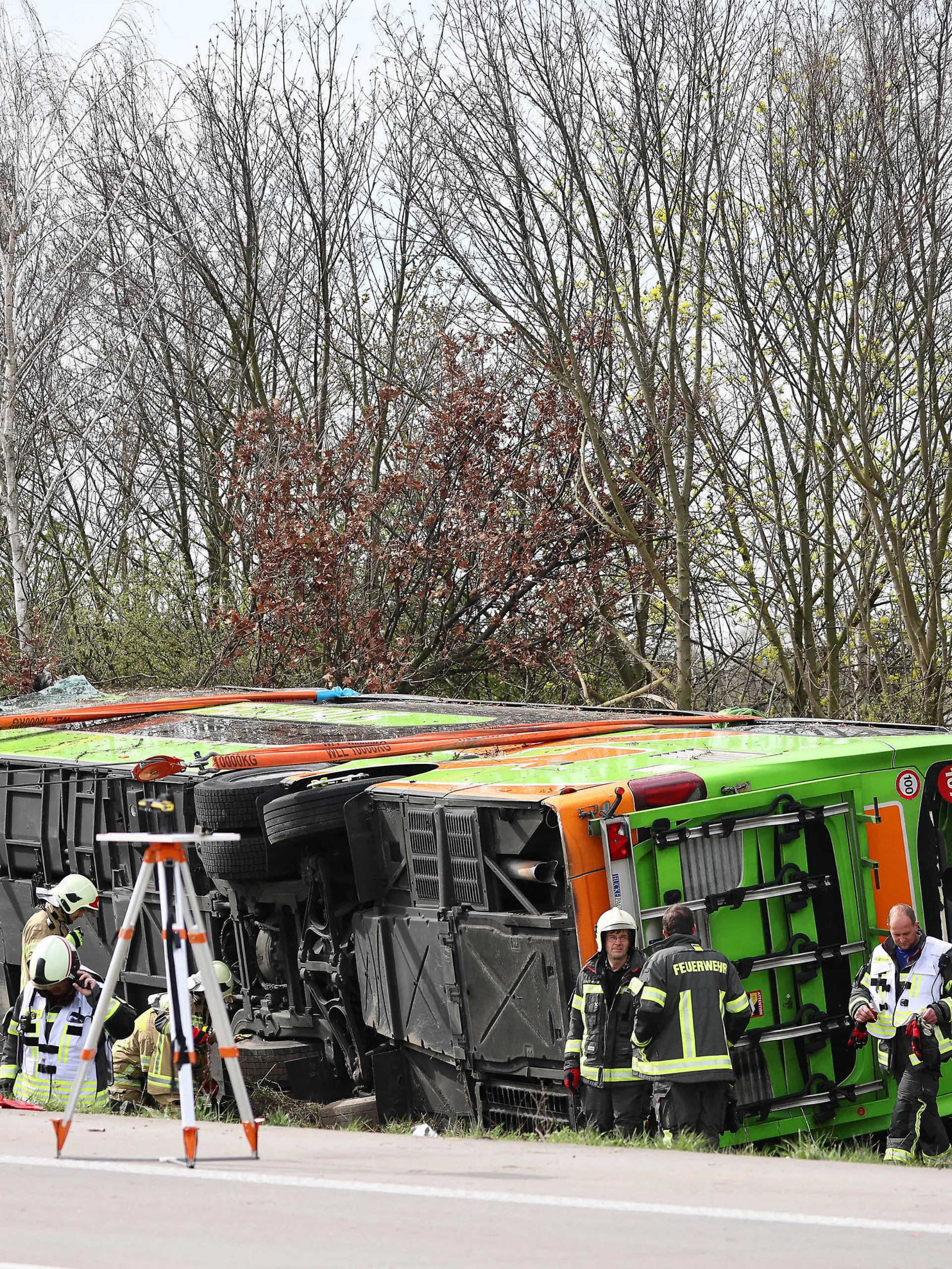 27.03.2024, Sachsen, Schkeuditz: Ein Reisebus liegt zur Seite gekippt an der Unfallstelle auf der A9. Bei einem Unfall mit einem Reisebus auf der A9 nahe Leipzig sind mindestens fünf Menschen ums Leben gekommen. Dies teilte die Polizei auf Anfrage mit. Zudem gab es bei dem Unfall am Mittwoch zahlreiche Verletzte. Foto: Jan Woitas/dpa +++ dpa-Bildfunk +++