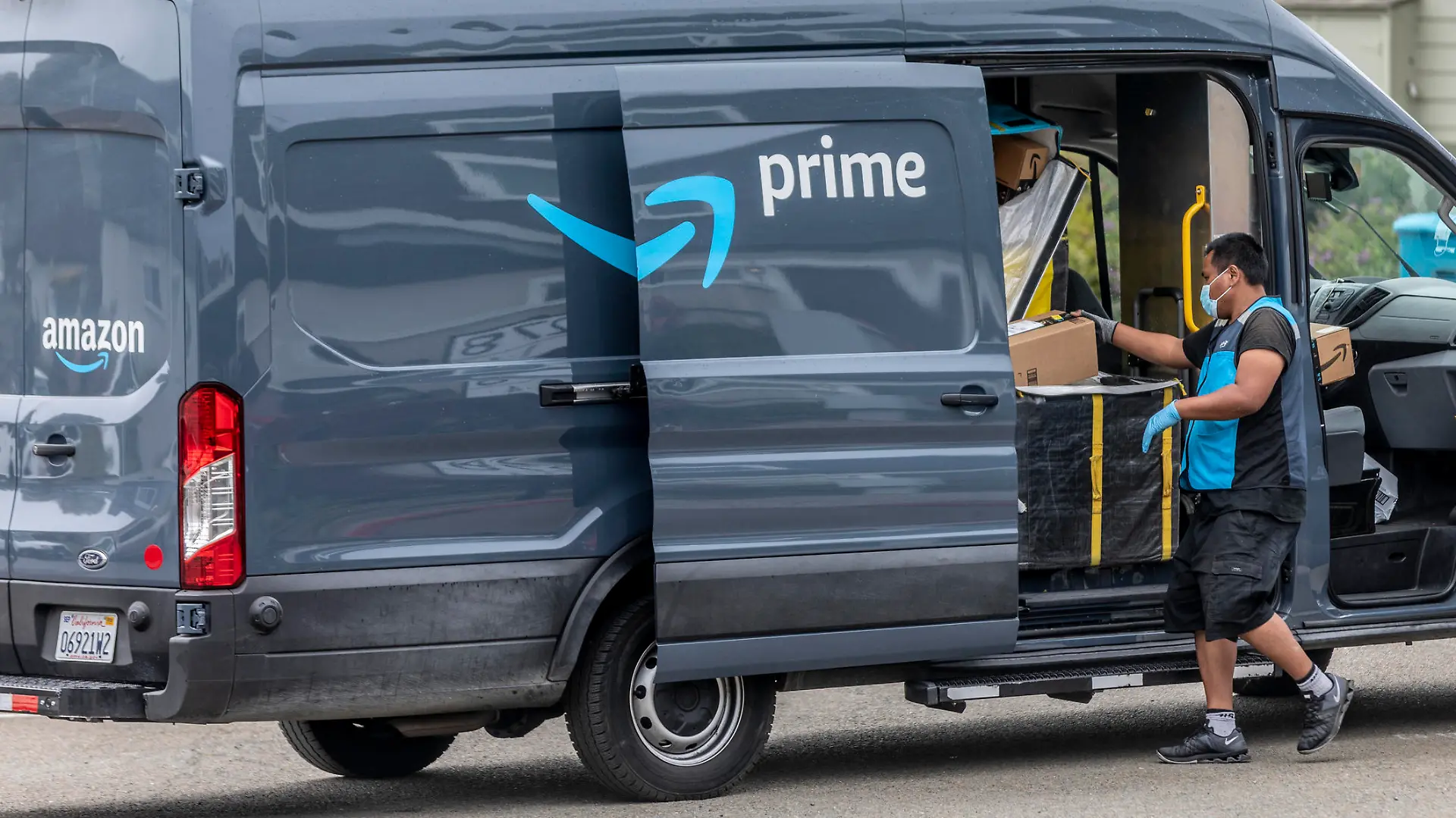 Pacifica California, USA - May 11, 2020: An Amazon Prime delivery driver wearing personal protective equipment delivers packages during the shelter in place order and quarantine.