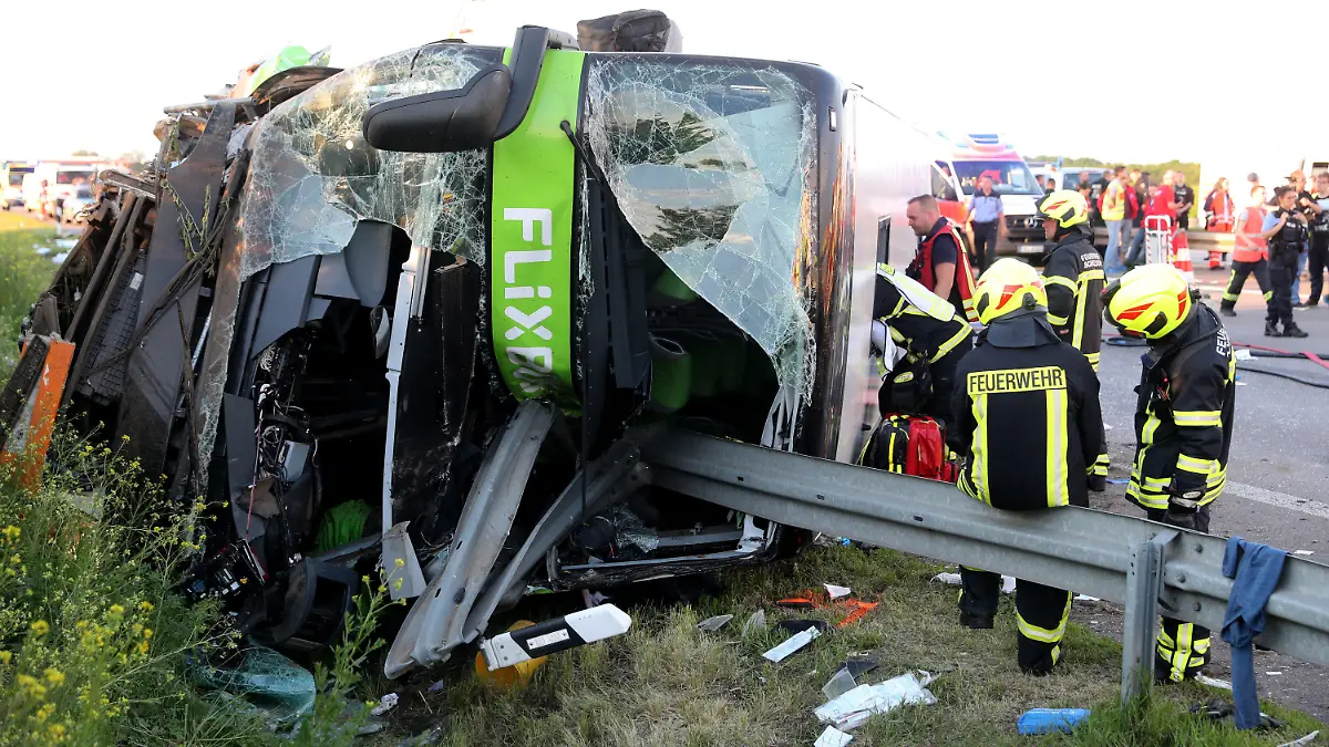 19.05.2019, Sachsen, Leipzig: Einsatzkräfte der Feuerwehr stehen an der Unfallstelle neben dem verunglückten Bus. Bei einem schweren Unfall mit einem Reisebus sind auf der Autobahn 9 nahe Leipzig mindestens ein Mensch getötet und zahlreiche Menschen verletzt worden. Demnach überschlug sich der Bus des Unternehmens Flixbus zwischen den Anschlussstellen Leipzig-West und Bad Dürrenberg. Anschließend blieb das Fahrzeug auf der Seite liegen. Foto: Jan Woitas/dpa-Zentralbild/dpa +++ dpa-Bildfunk +++