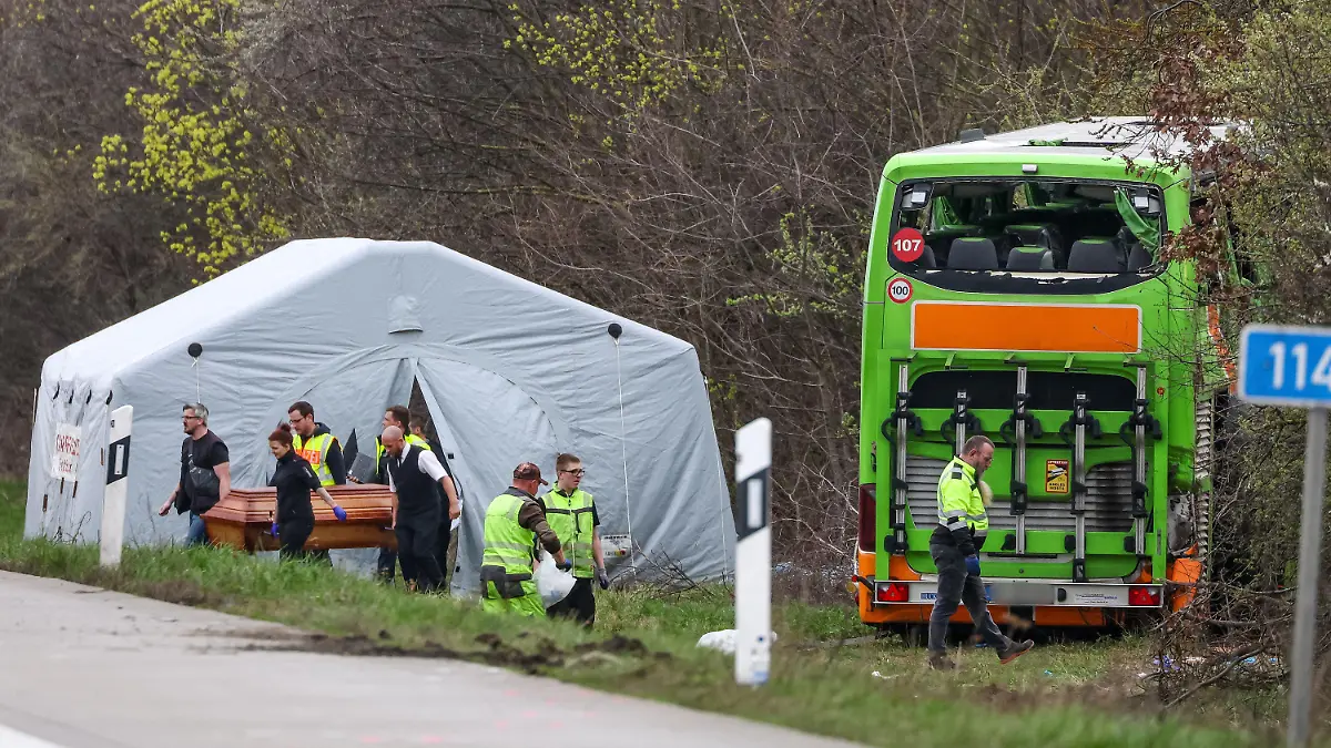 27.03.2024, Sachsen, Schkeuditz: Bestatter tragen ein Todesopfer des verunglückten Busses von der Unfallstelle auf der A9. Bei dem Unfall mit einem Reisebus auf der A9 nahe Leipzig sind mindestens fünf Menschen ums Leben gekommen. Dies teilte die Polizei auf Anfrage mit. Zudem gab es bei dem Unfall zahlreiche Verletzte. Foto: Jan Woitas/dpa - ACHTUNG: Kennzeichen wurde aus rechtlichen Gründen gepixelt +++ dpa-Bildfunk +++