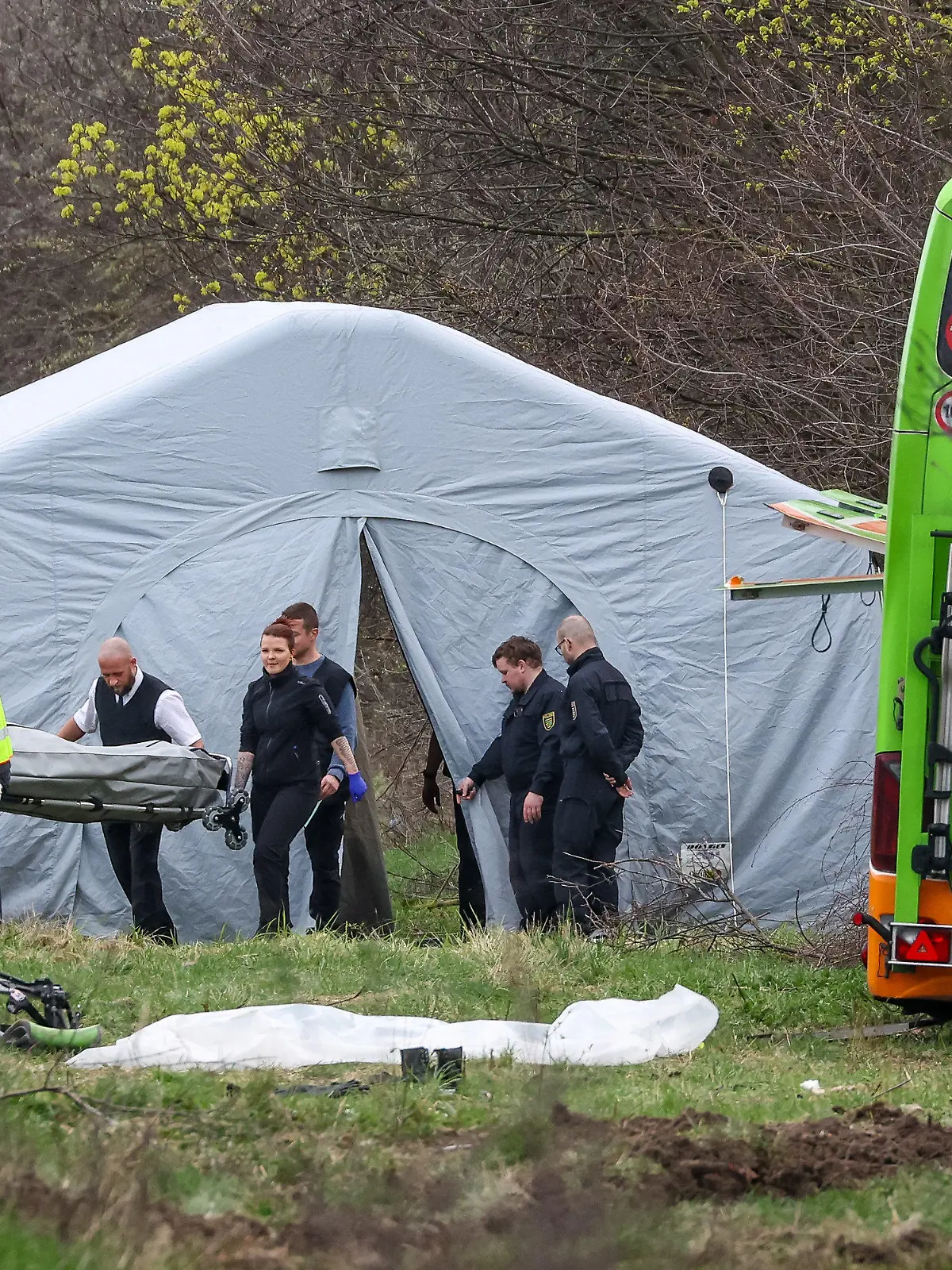 dpatopbilder - 27.03.2024, Sachsen, Schkeuditz: Bestatter tragen ein Todesopfer des verunglückten Busses von der Unfallstelle auf der A9. Bei dem Unfall mit einem Reisebus auf der A9 nahe Leipzig sind mindestens fünf Menschen ums Leben gekommen. Dies teilte die Polizei auf Anfrage mit. Zudem gab es bei dem Unfall zahlreiche Verletzte. Foto: Jan Woitas/dpa - ACHTUNG: Kennzeichen wurde aus rechtlichen Gründen gepixelt +++ dpa-Bildfunk +++