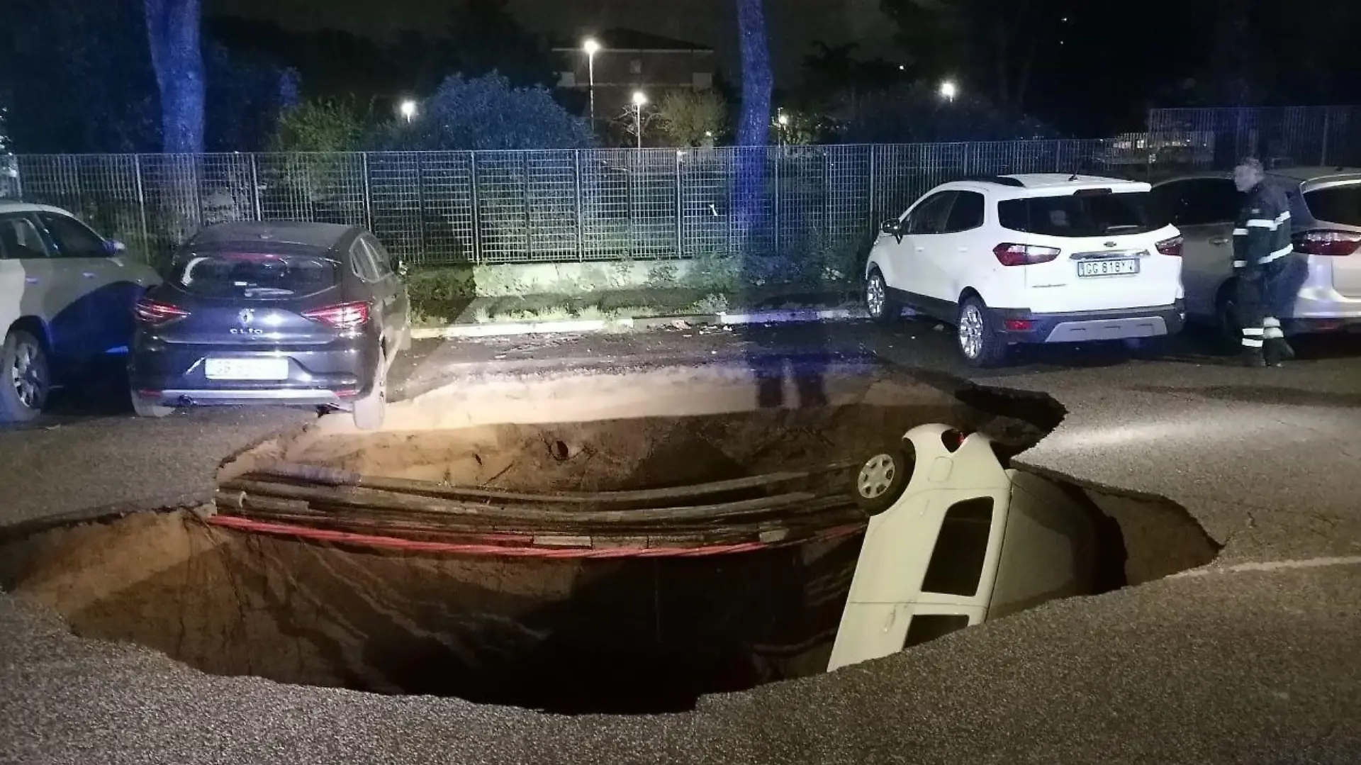HANDOUT - 28.03.2024, Italien, Rom: Autos liegen in einem riesigen Erdloch. Das ungefähr zehn Meter tiefe Loch mit einem Durchmesser von ebenfalls zirka zehn Metern hatte sich aus bisher ungeklärter Ursache in der Nacht zum 28.03.2024 aufgetan und zwei geparkte Autos in die Tiefe gerissen. Foto: Polizia Roma Capitale/dpa - ACHTUNG: Nur zur redaktionellen Verwendung im Zusammenhang mit der aktuellen Berichterstattung und nur mit vollständiger Nennung des vorstehenden Credits +++ dpa-Bildfunk +++