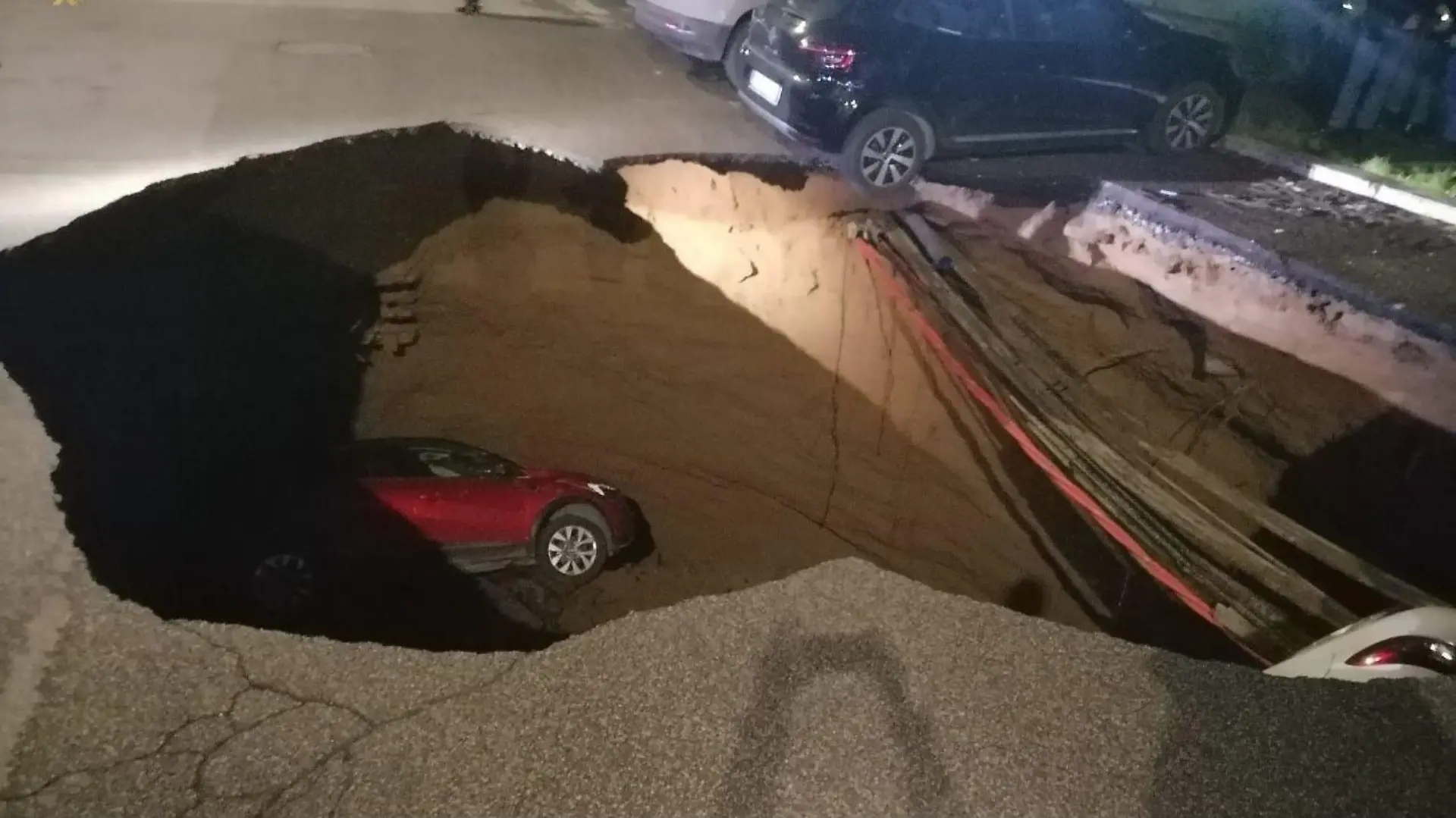 HANDOUT - 28.03.2024, Italien, Rom: Autos liegen in einem riesigen Erdloch. Das ungefähr zehn Meter tiefe Loch mit einem Durchmesser von ebenfalls zirka zehn Metern hatte sich aus bisher ungeklärter Ursache in der Nacht zum 28.03.2024 aufgetan und zwei geparkte Autos in die Tiefe gerissen. Foto: Polizia Roma Capitale/dpa - ACHTUNG: Nur zur redaktionellen Verwendung im Zusammenhang mit der aktuellen Berichterstattung und nur mit vollständiger Nennung des vorstehenden Credits +++ dpa-Bildfunk +++