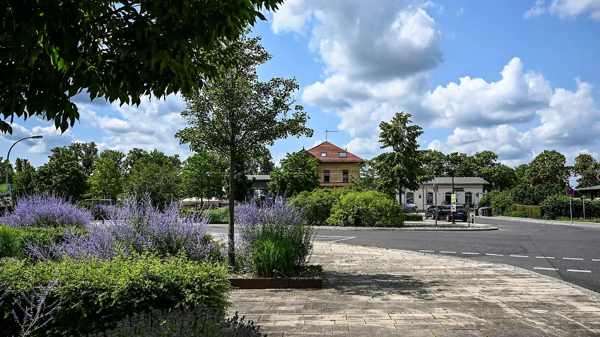 Begrünt, bepflanzt und mit Bänken und Papierkörben ist der Bahnhofsvorplatz am Bahnhof.