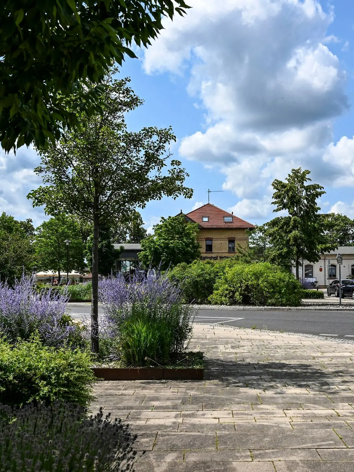 Begrünt, bepflanzt und mit Bänken und Papierkörben ist der Bahnhofsvorplatz am Bahnhof.