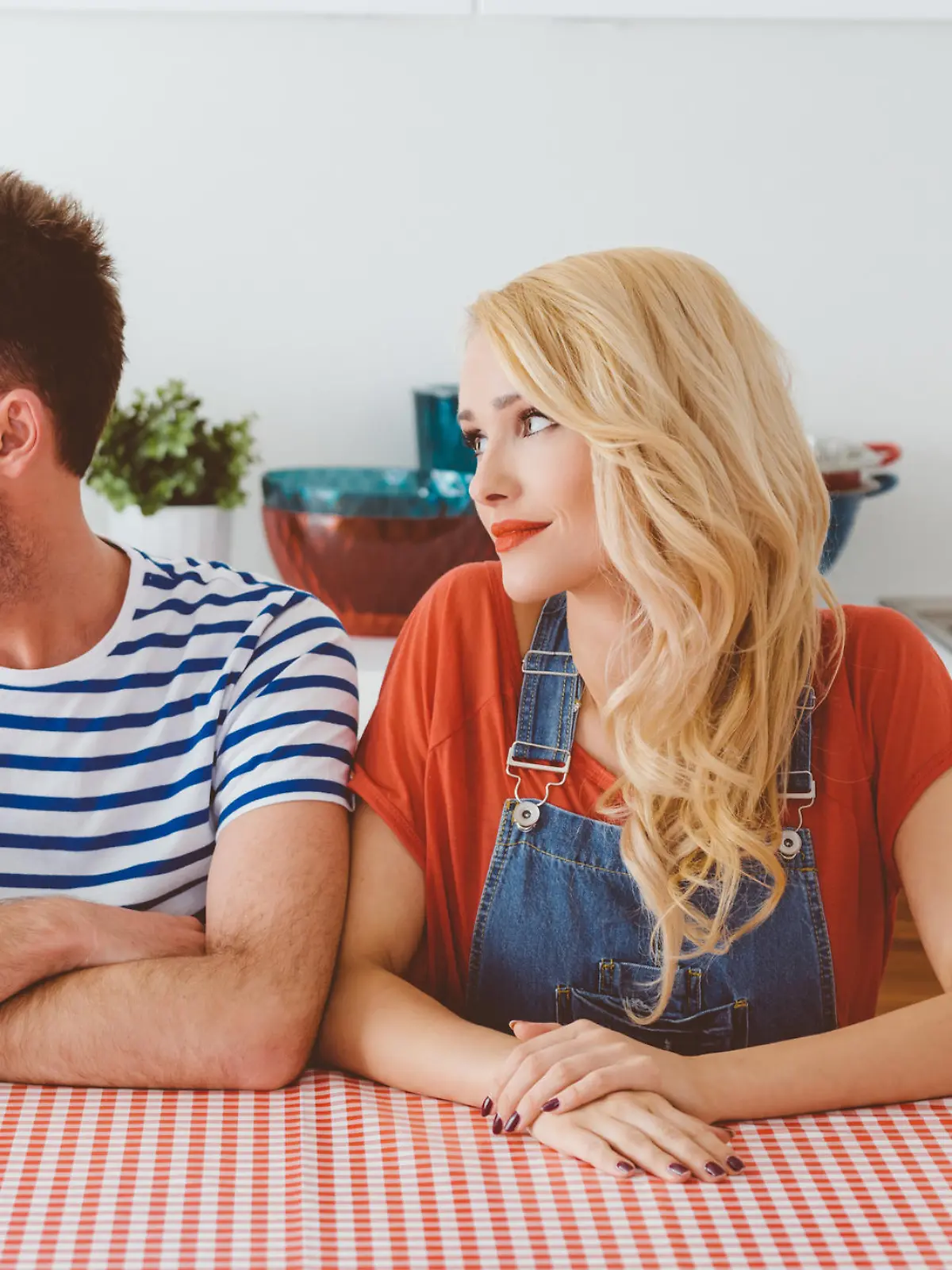 Middle aged couple sitting at the table in the kitchen at home, not speaking. 