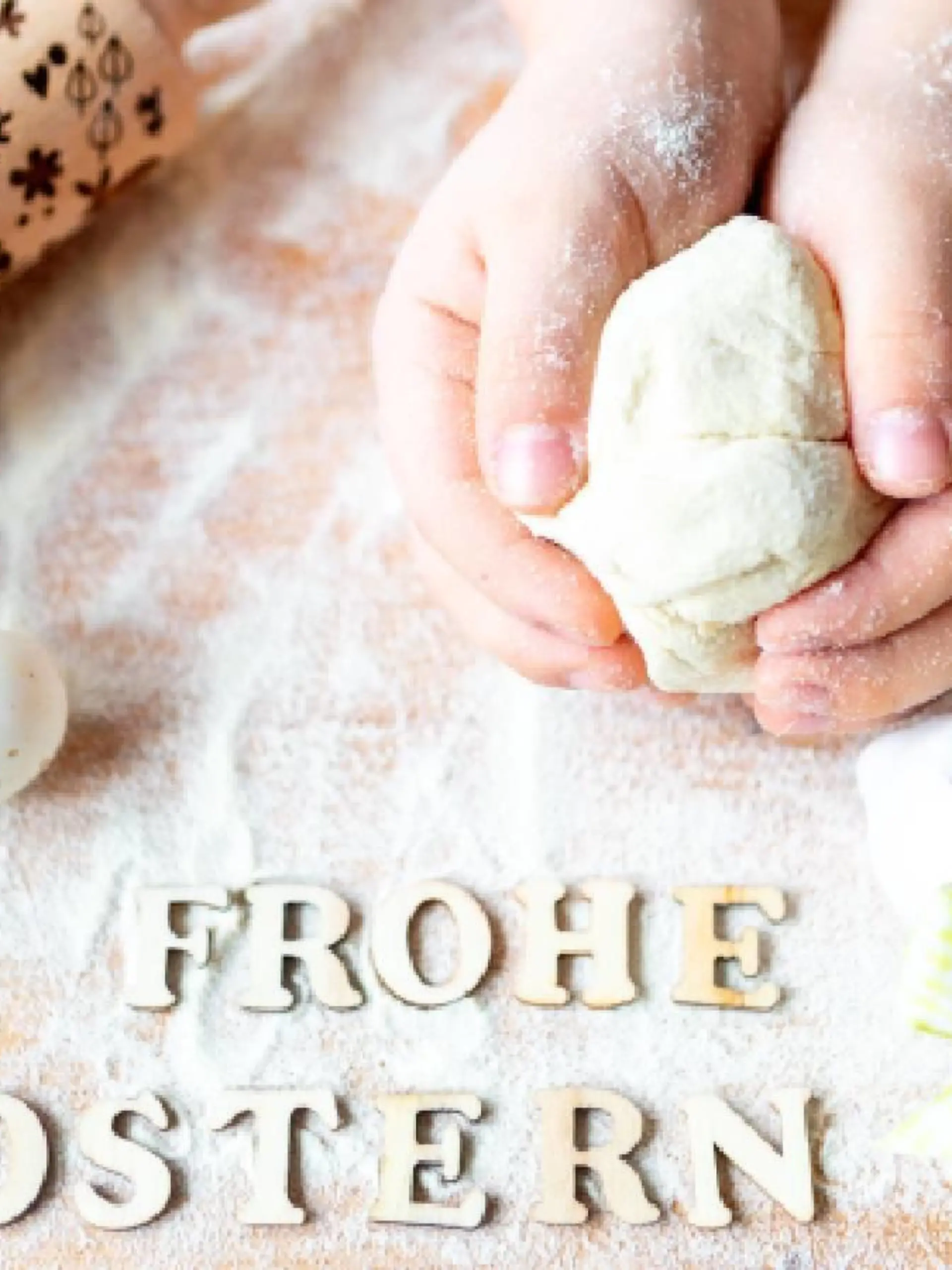 Backen an Ostern Konzept, Backzutaten wie Mehl und Eier auf einer Arbeitsplatte mit Kinderhänden und dem Schriftzug: Frohe Ostern